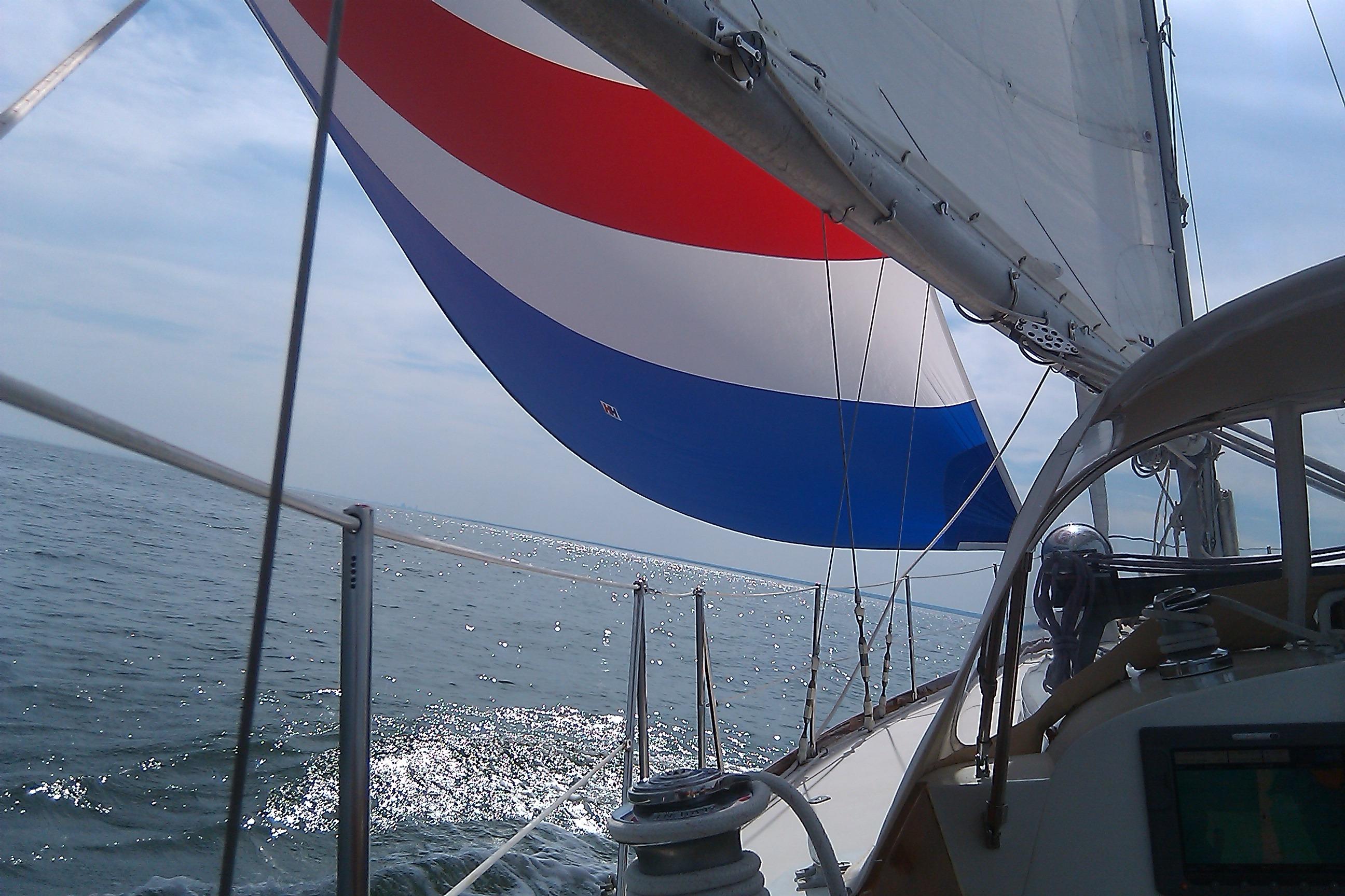 Hinckley Bermuda 40 sailboat from 1970 with colorful spinnaker on open sea.