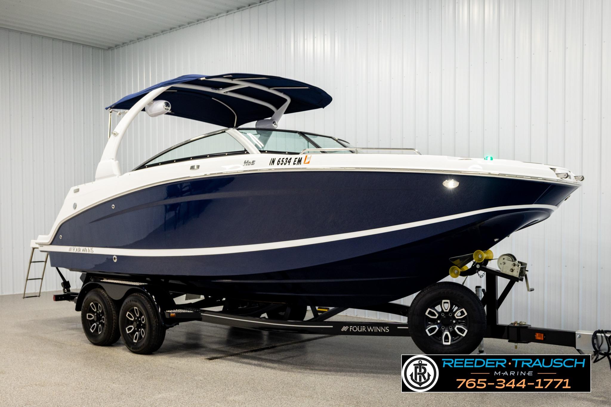2024 FOURWINNS HD5 Surf boat on trailer in indoor showroom.