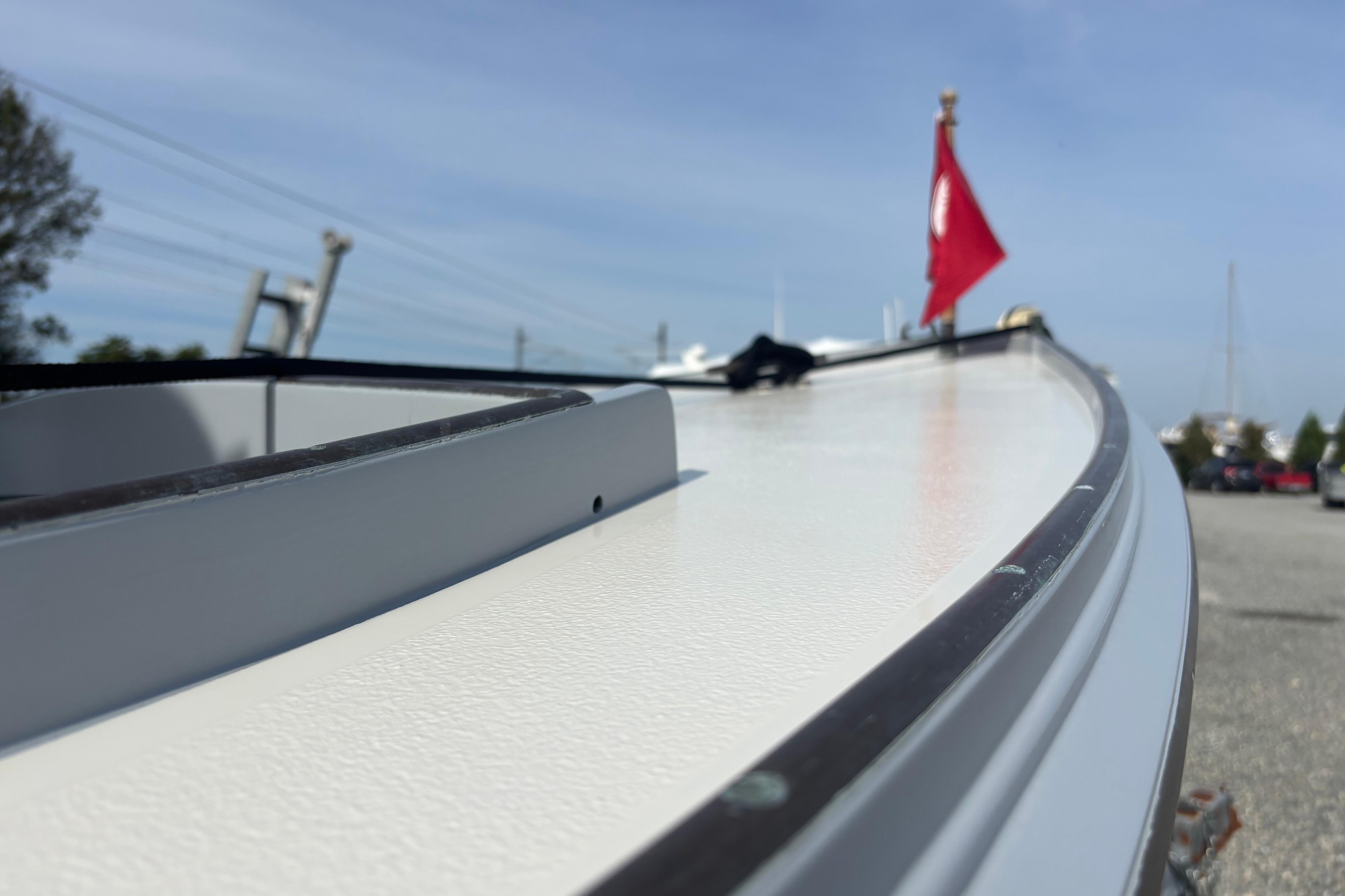 Custom 2005 model boat with red flag, docked on a sunny day.