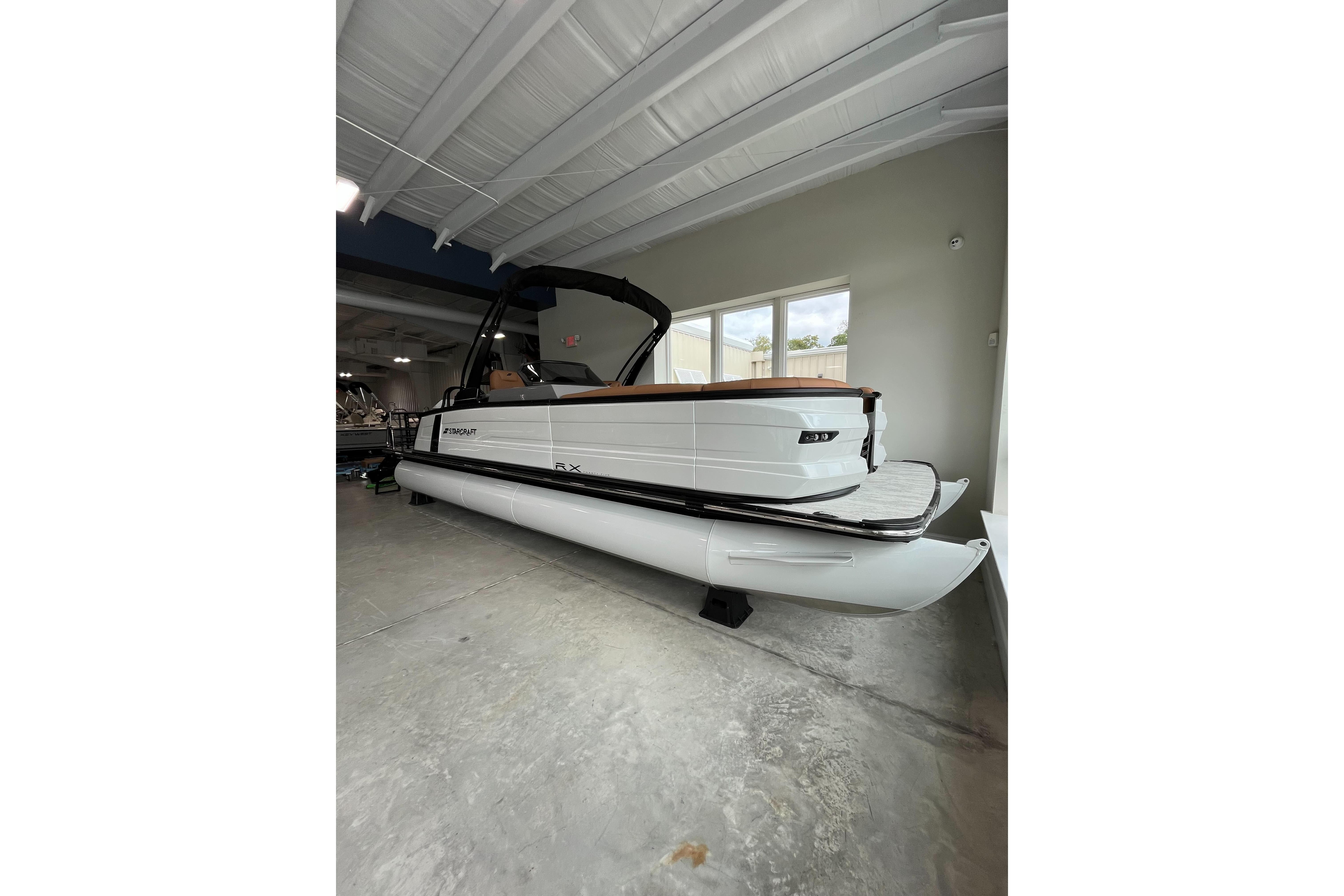 2026 Starcraft RX 25 DL DC pontoon boat in showroom, side view.