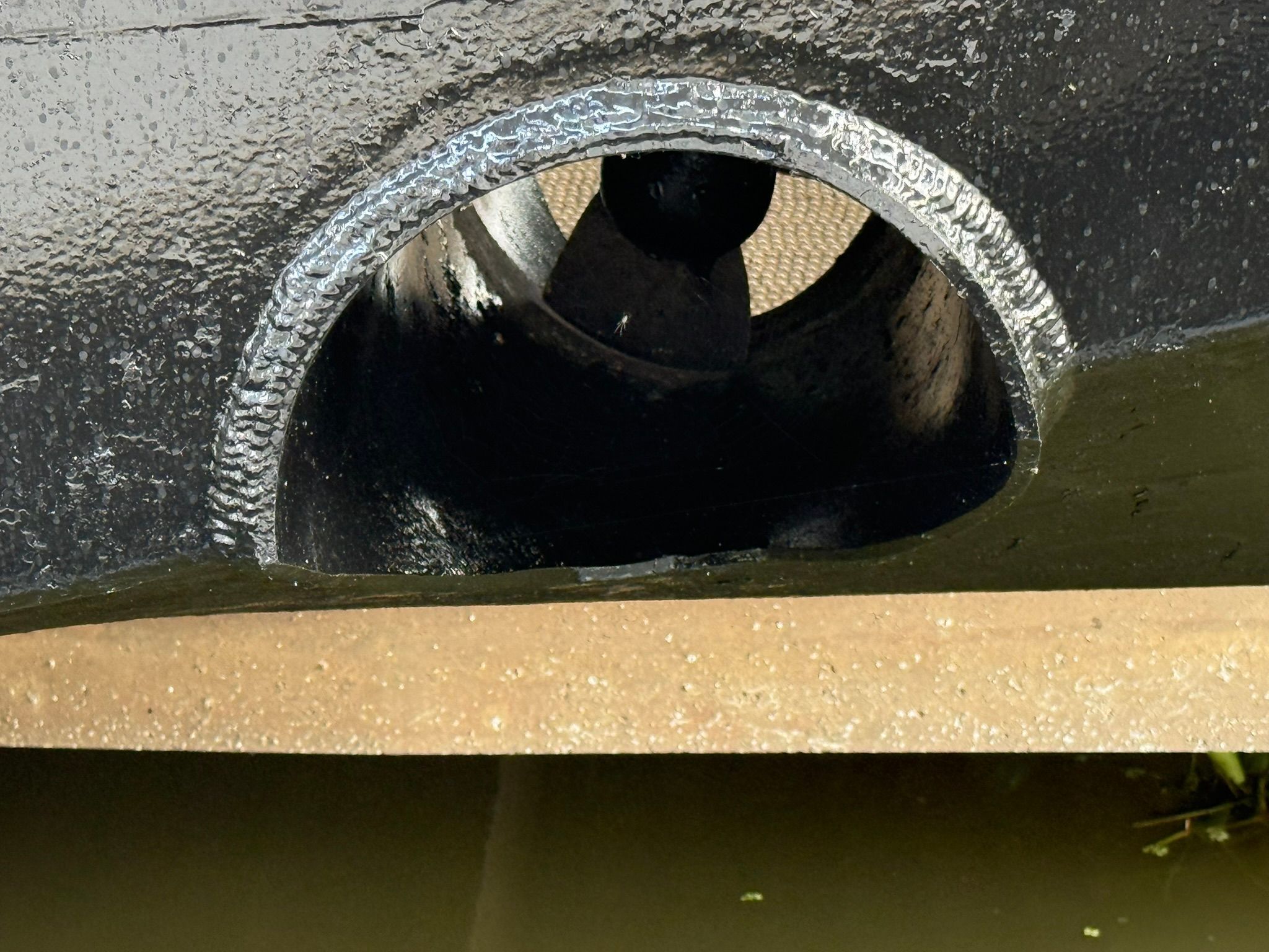 Close-up of a black boat hull with an opening and a propeller.