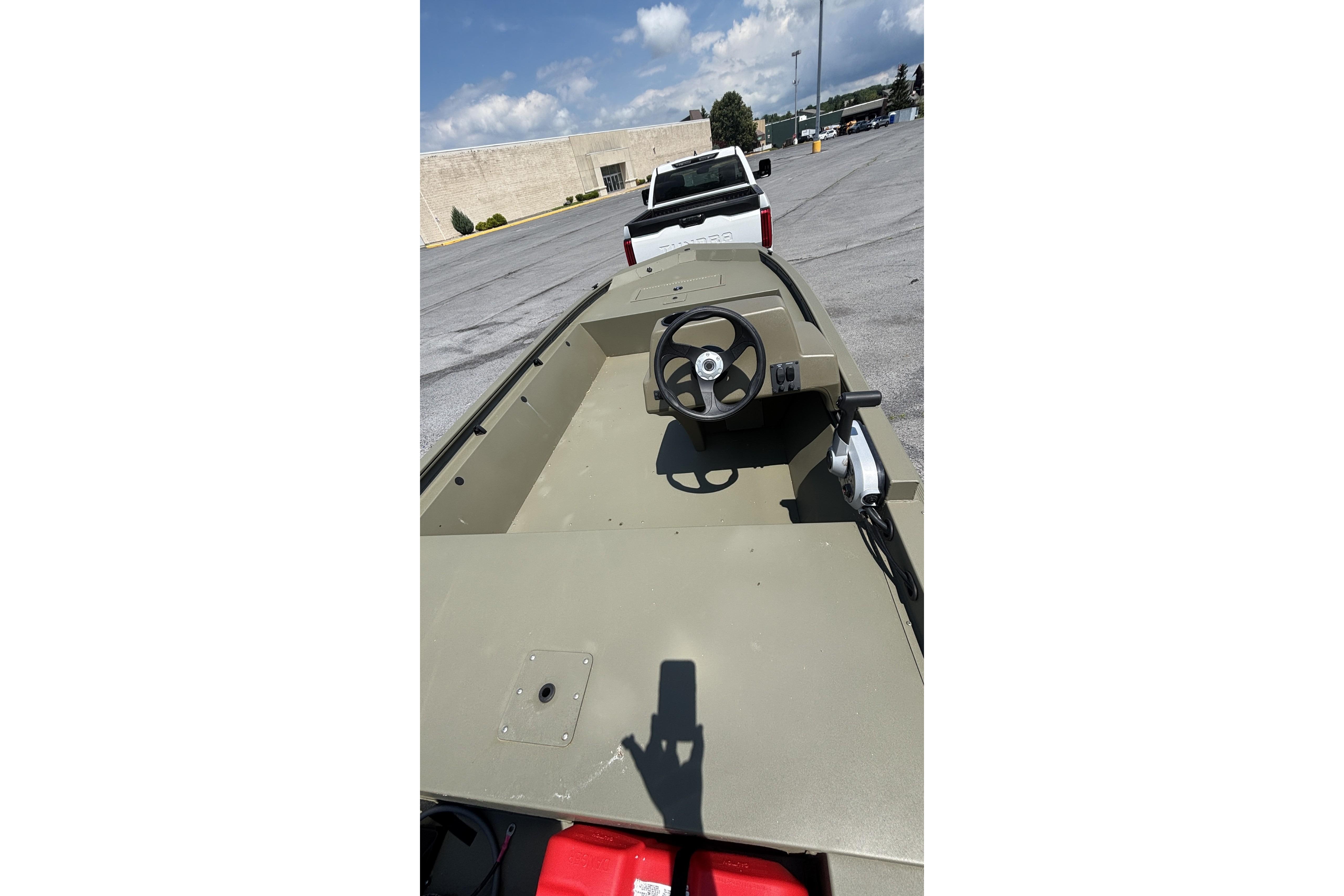 2026 Tracker Grizzly 1648 SC boat in parking lot, steering wheel visible.