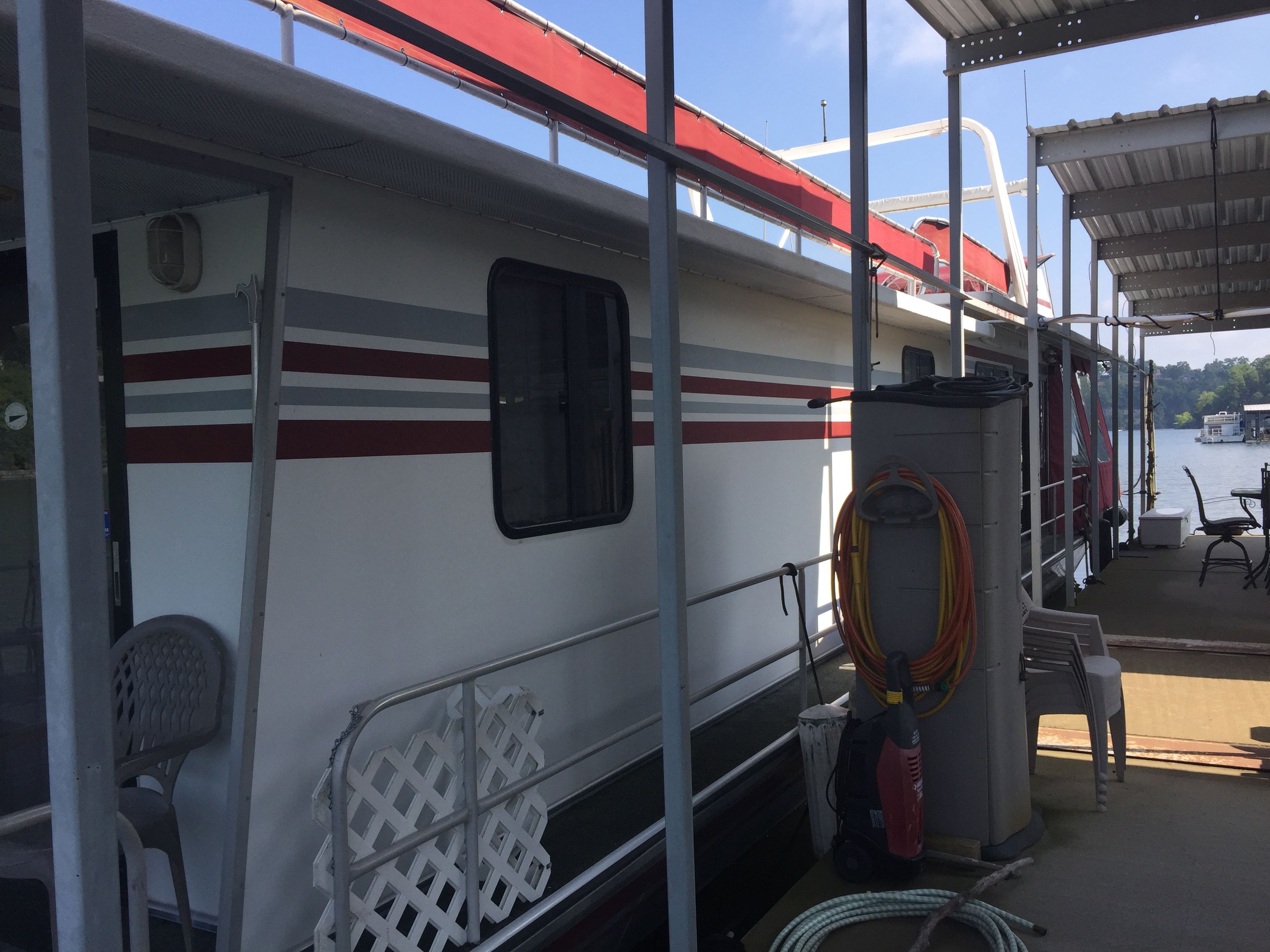 A 1989 Sumerset houseboat docked. It features red and gray stripes.