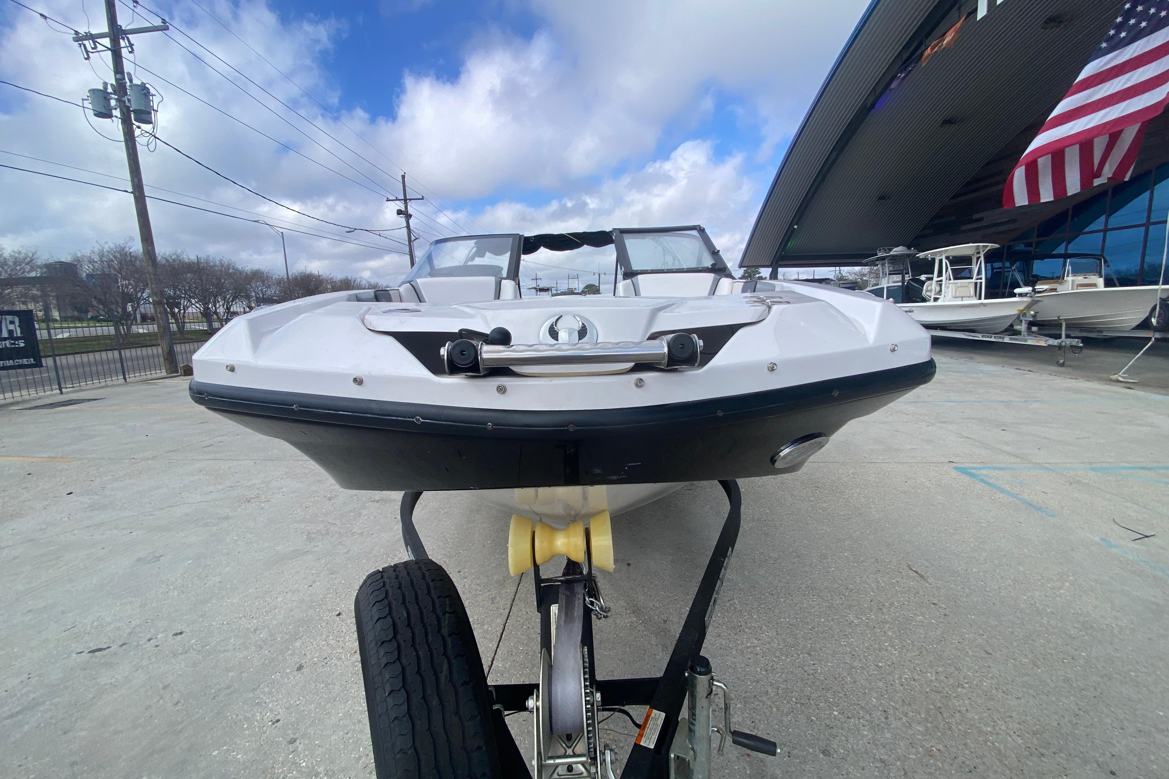 2018 Scarab 215 G boat on trailer, parked outside dealership under cloudy sky.