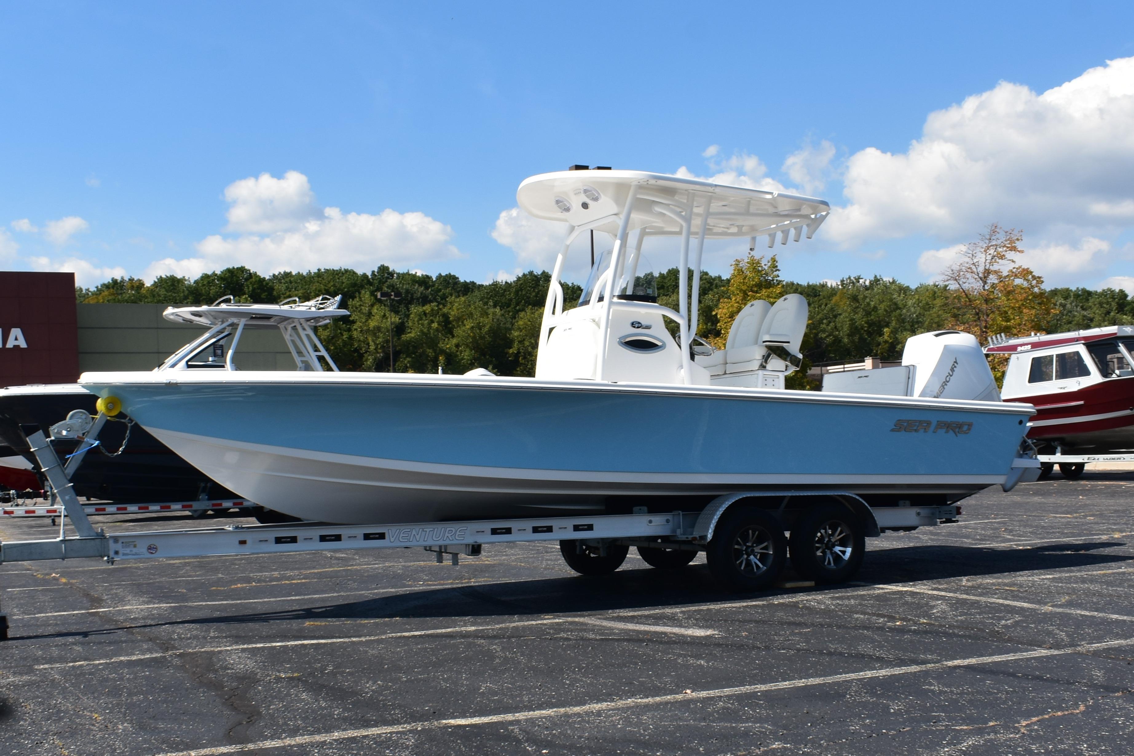 2025 Sea Pro 250 Bay boat on trailer, parked outdoors under blue sky.