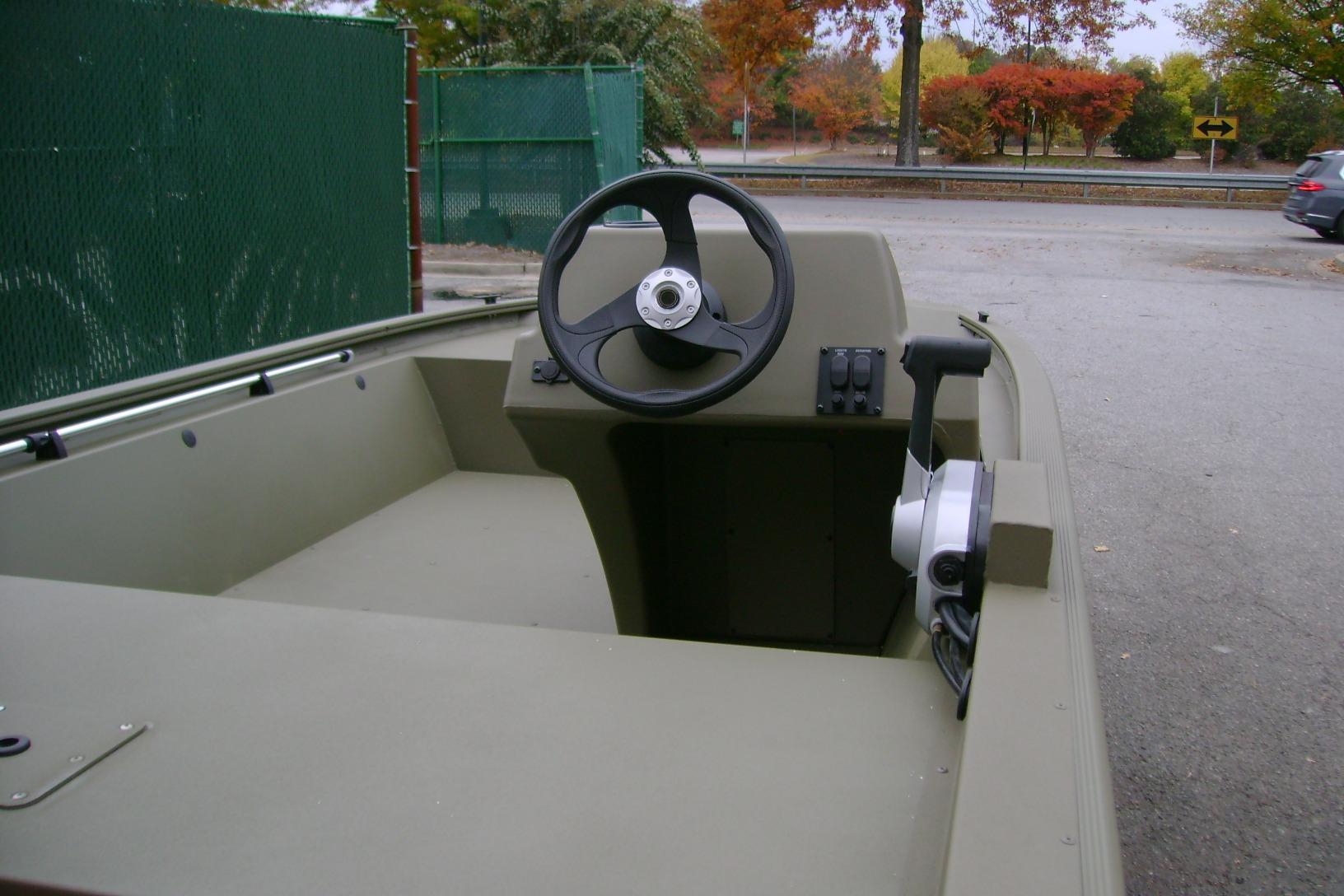 2026 Tracker Grizzly 1648 SC boat interior with steering wheel, parked outdoors.