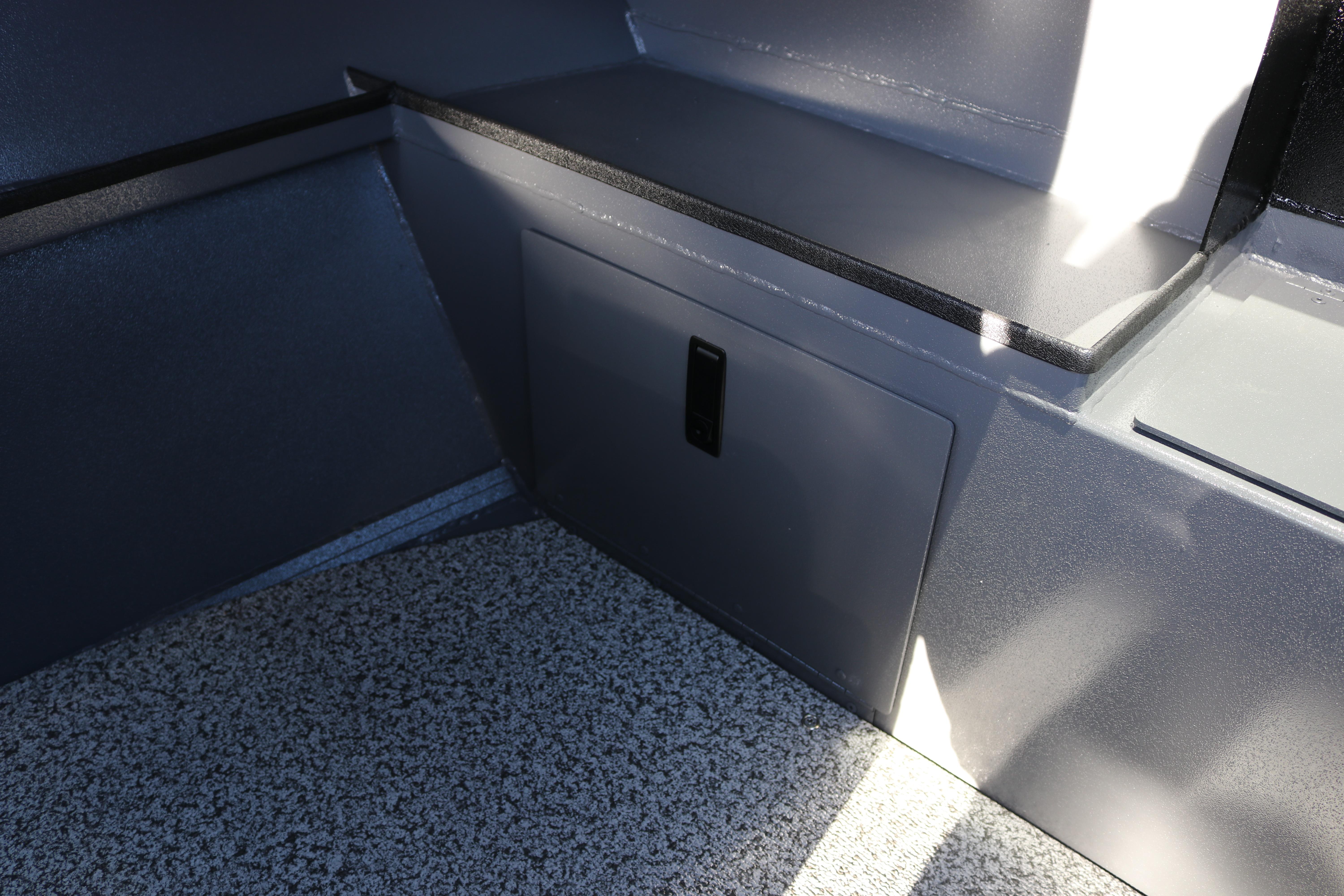 Interior view of 2026 Alumaweld Stryker X202 boat, featuring storage compartment and textured flooring.