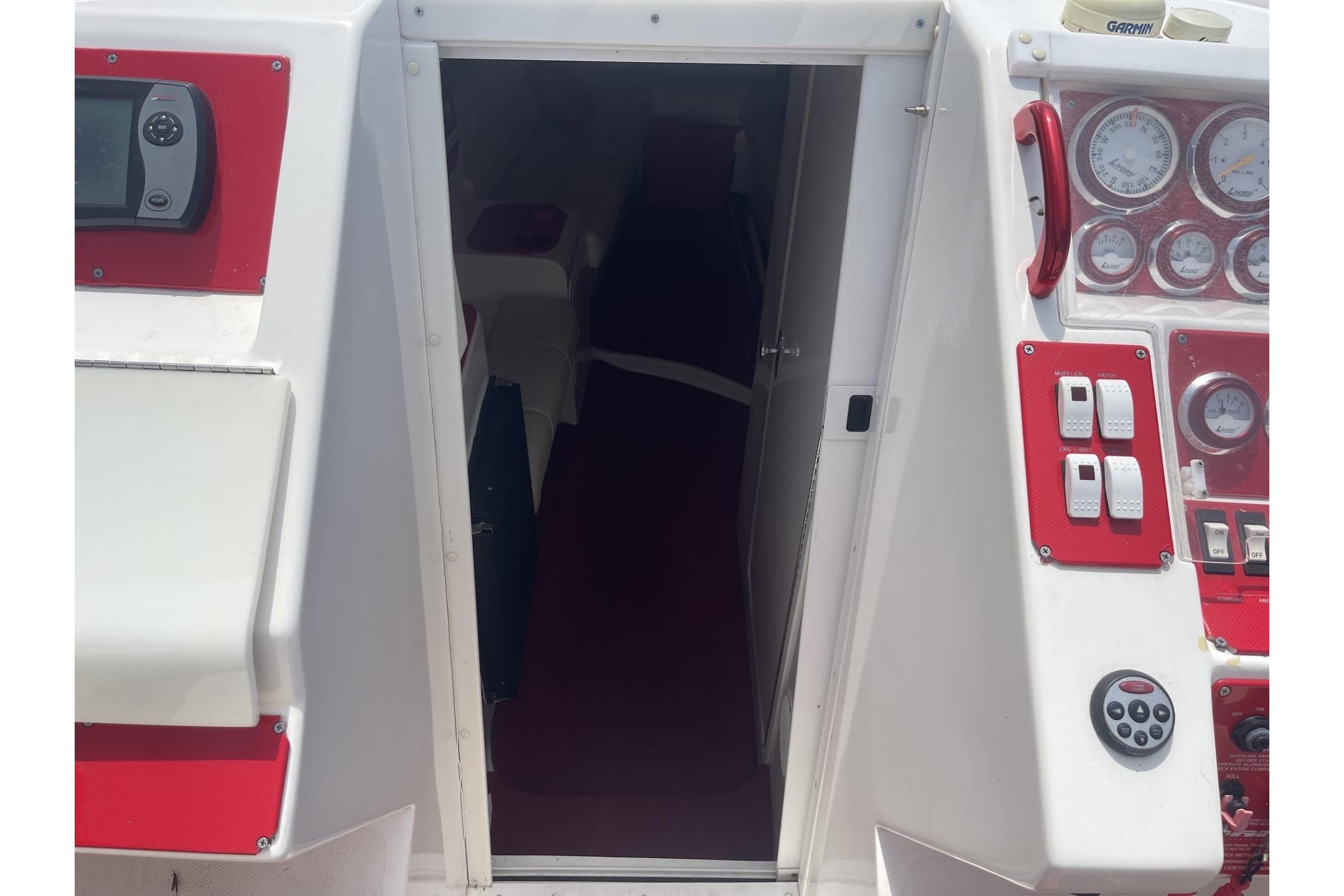 2006 Sonic 386 boat cockpit with red and white controls and open cabin door.