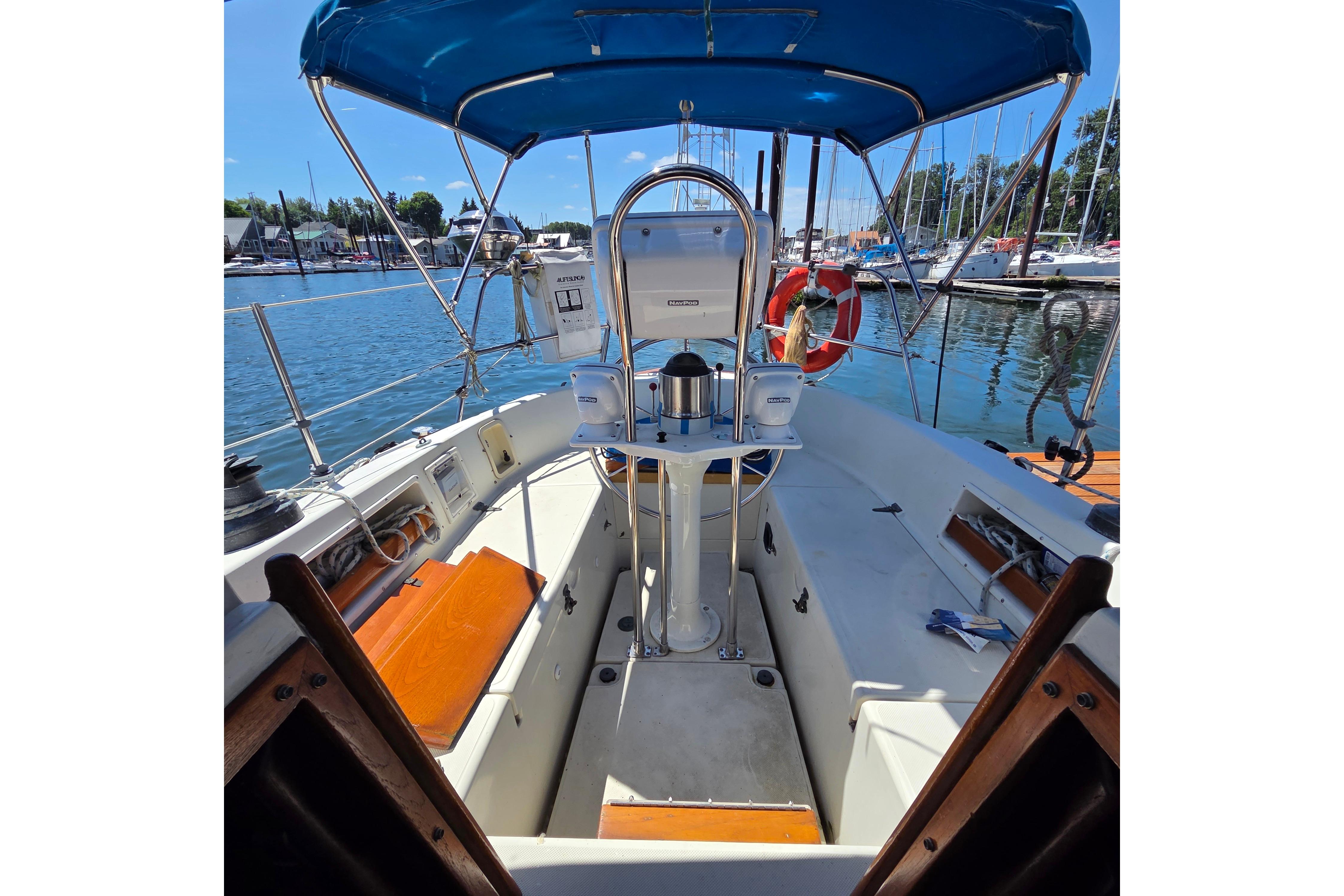 Cockpit of 1983 Pacific Seacraft 34 sailboat with blue canopy, docked in marina.