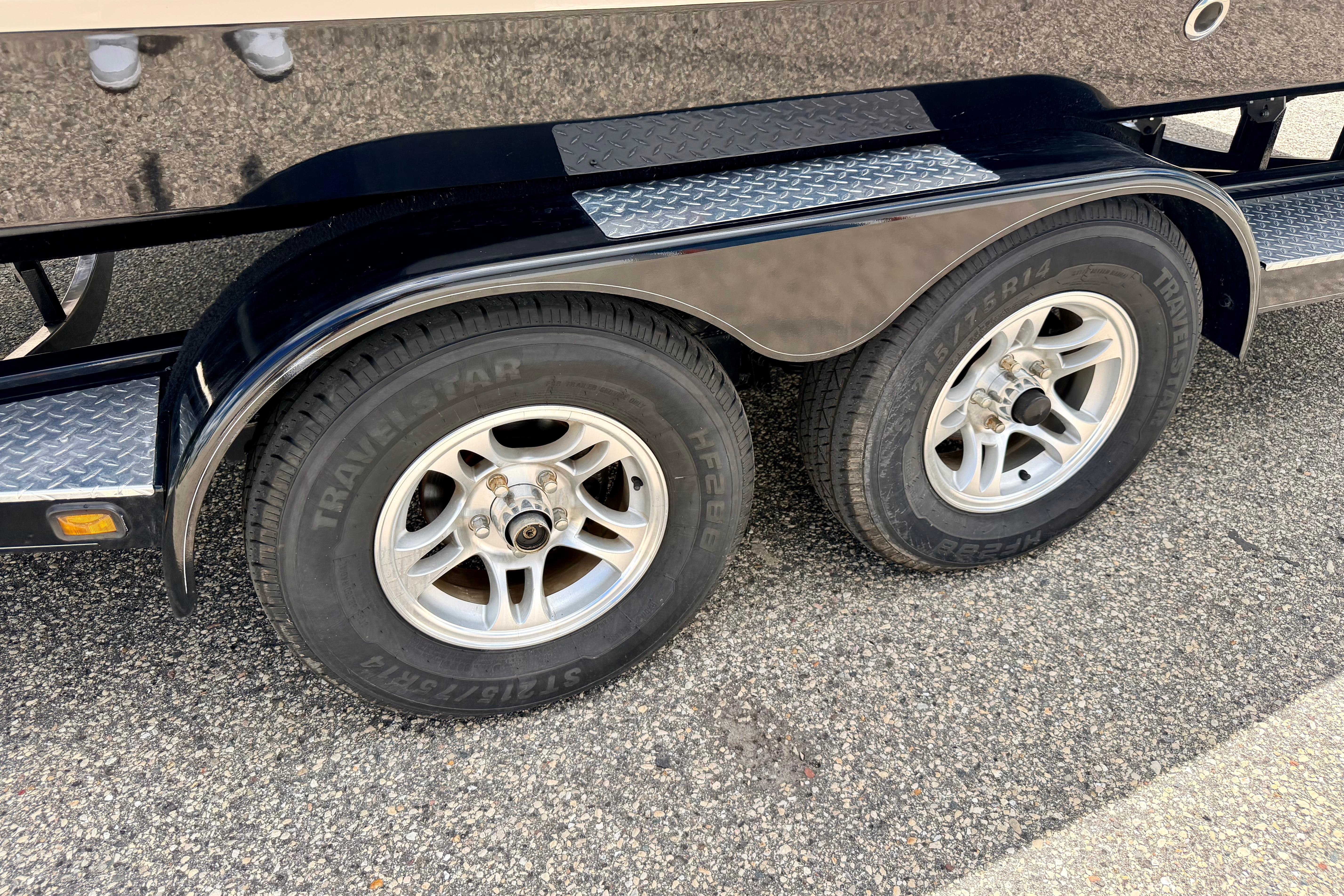 Trailer wheels of a 2015 Chaparral Sunesta 264 boat on pavement.