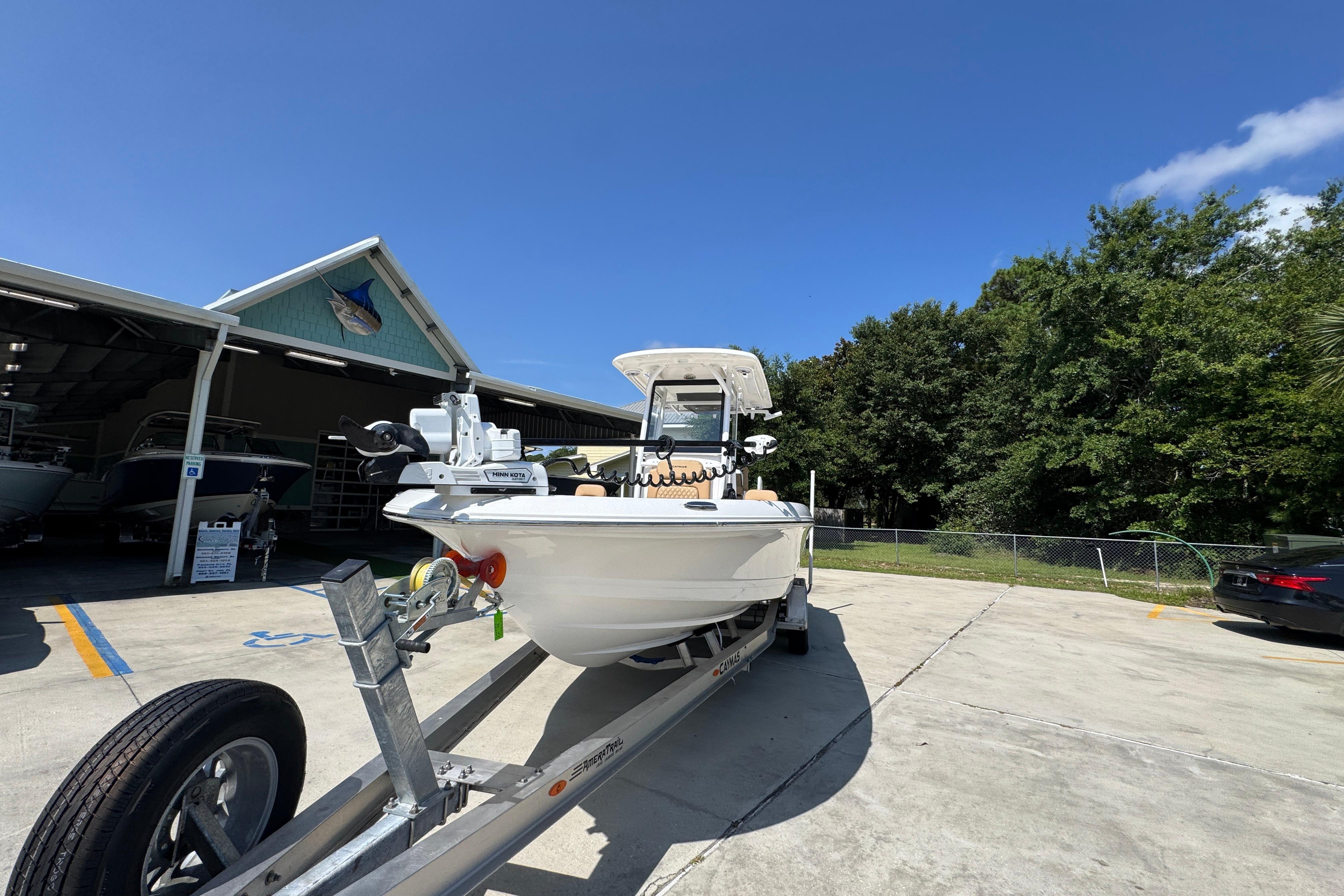 2027 Caymas 26 HB boat on trailer outside a showroom under clear blue sky.