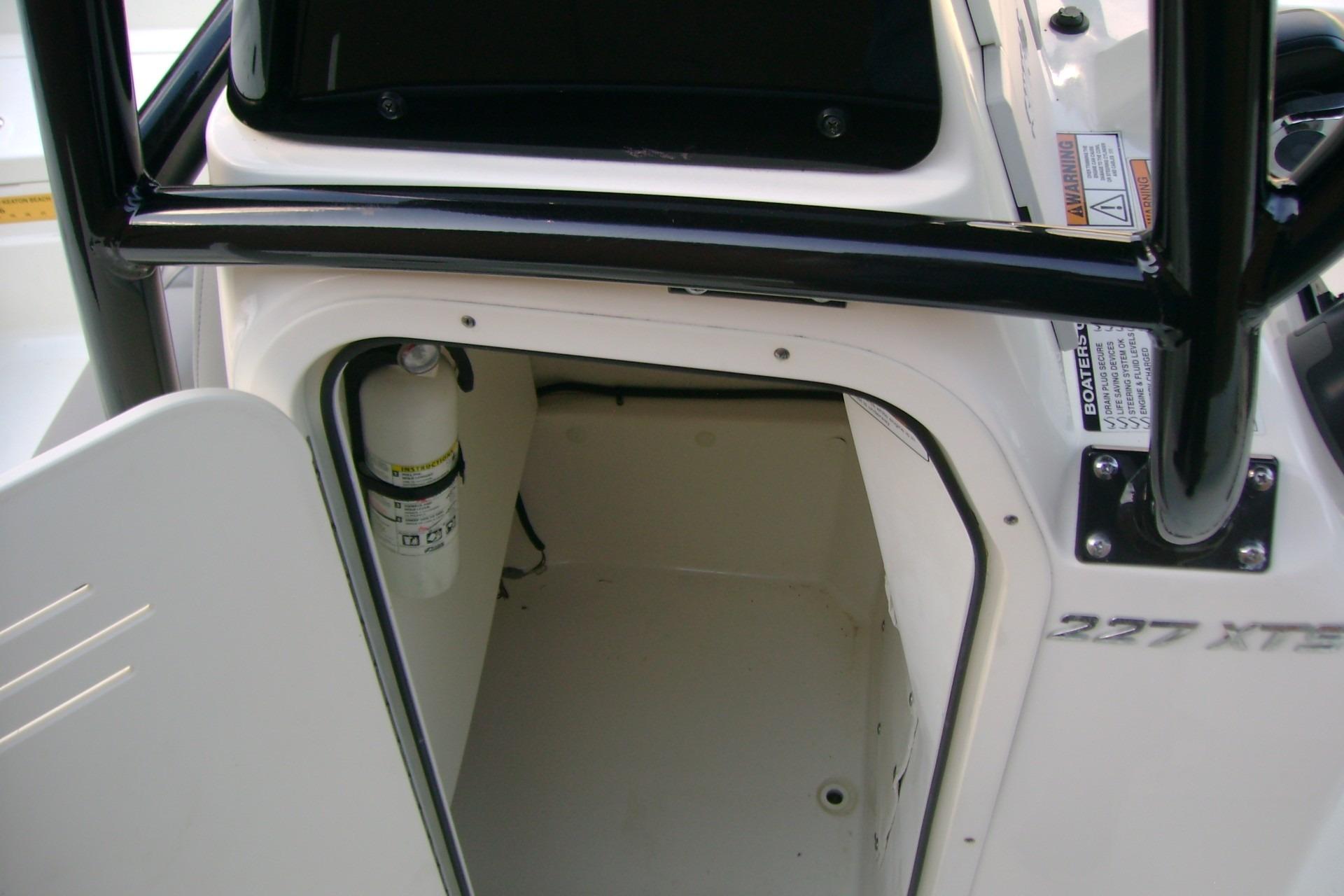 2022 NauticStar 227 XTS boat storage compartment with fire extinguisher.