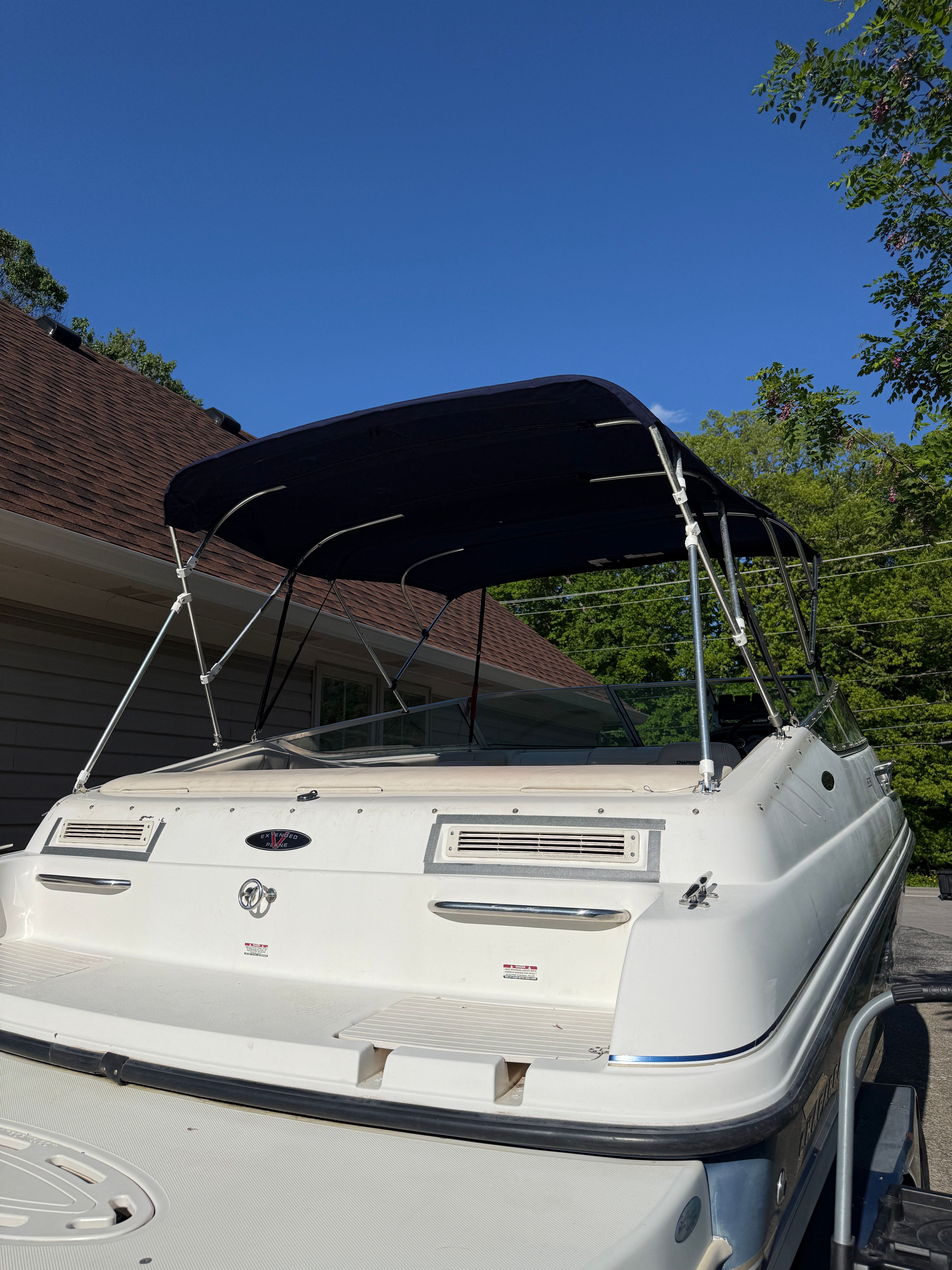 1999 Custom 2335 Cuddy Cabin boat with canopy, parked outdoors.