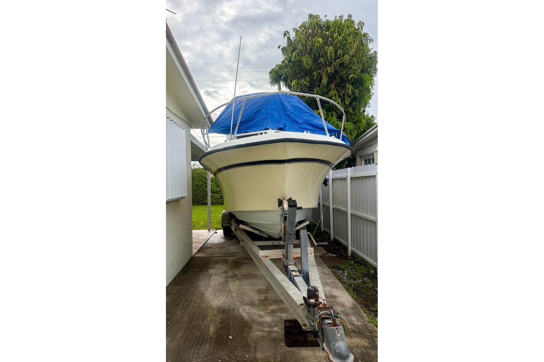 1989 Grady-White Offshore 242 boat on trailer, covered with blue tarp.