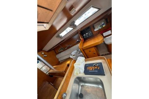 Interior of 1986 Beneteau First 305 sailboat, featuring a compact kitchen and cozy seating area.