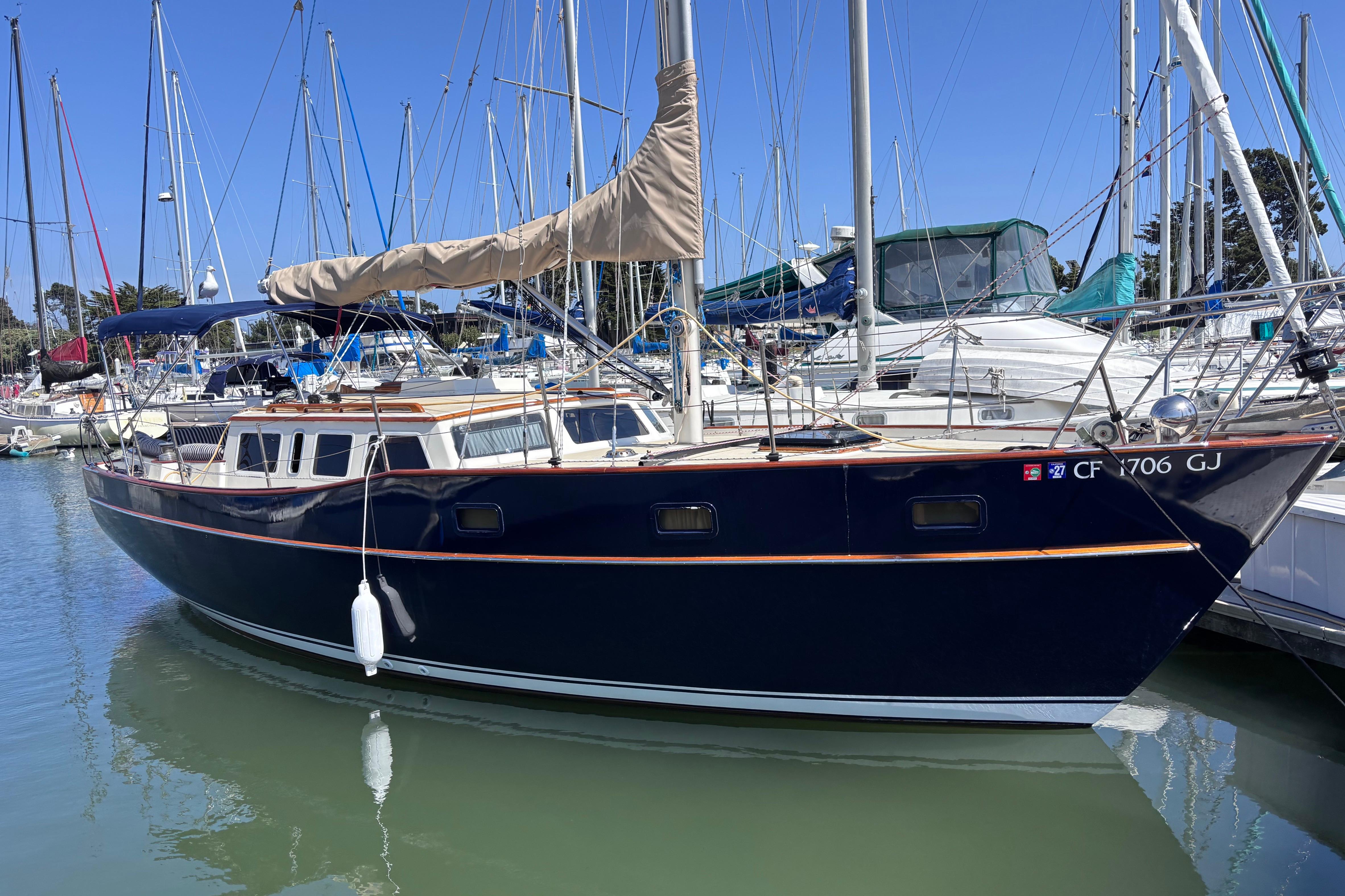 1978 Swift 33 sailboat docked in marina, featuring sleek navy hull and beige sail cover.