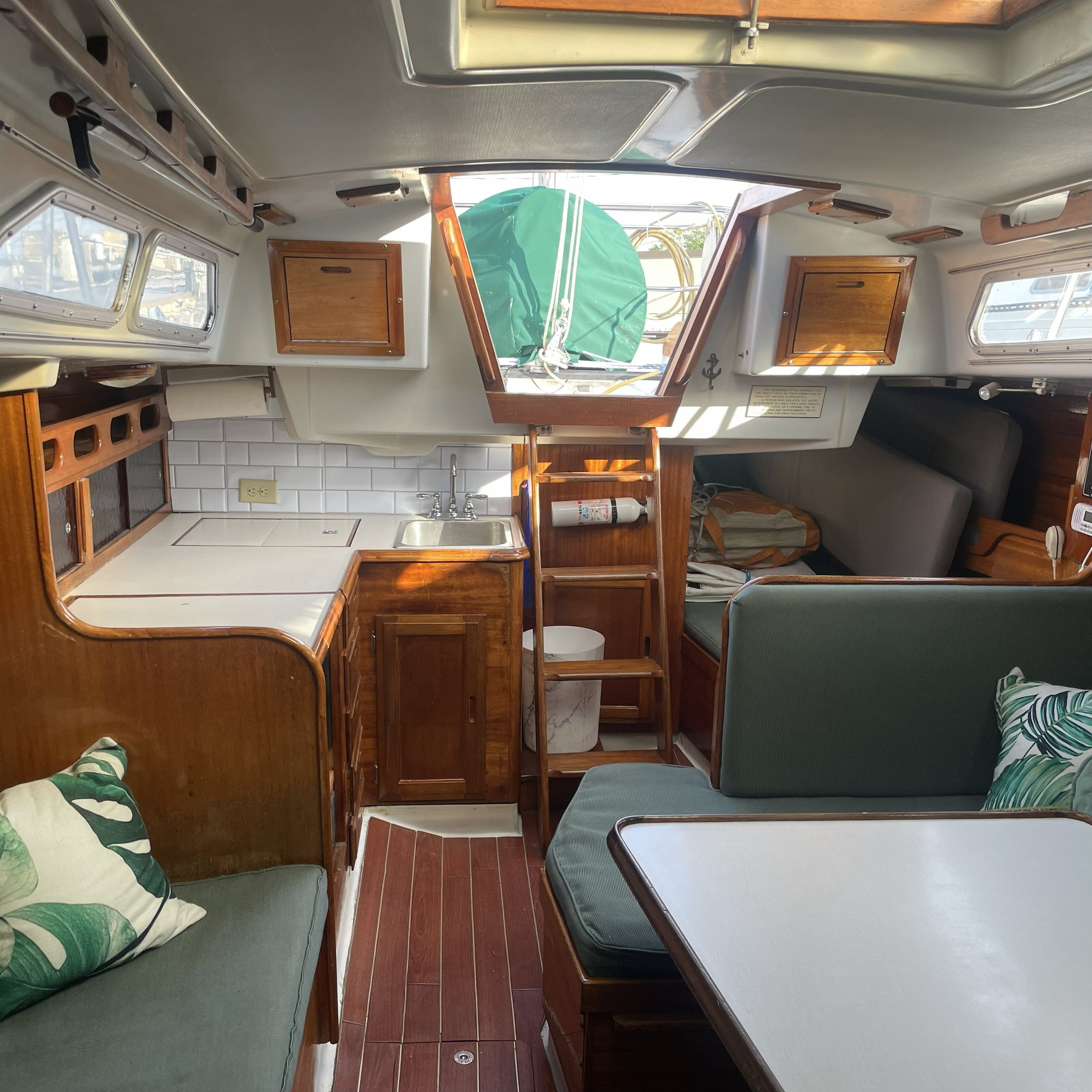 Interior of a 1974 Ericson 35 sailboat with wood finishes and green cushions.