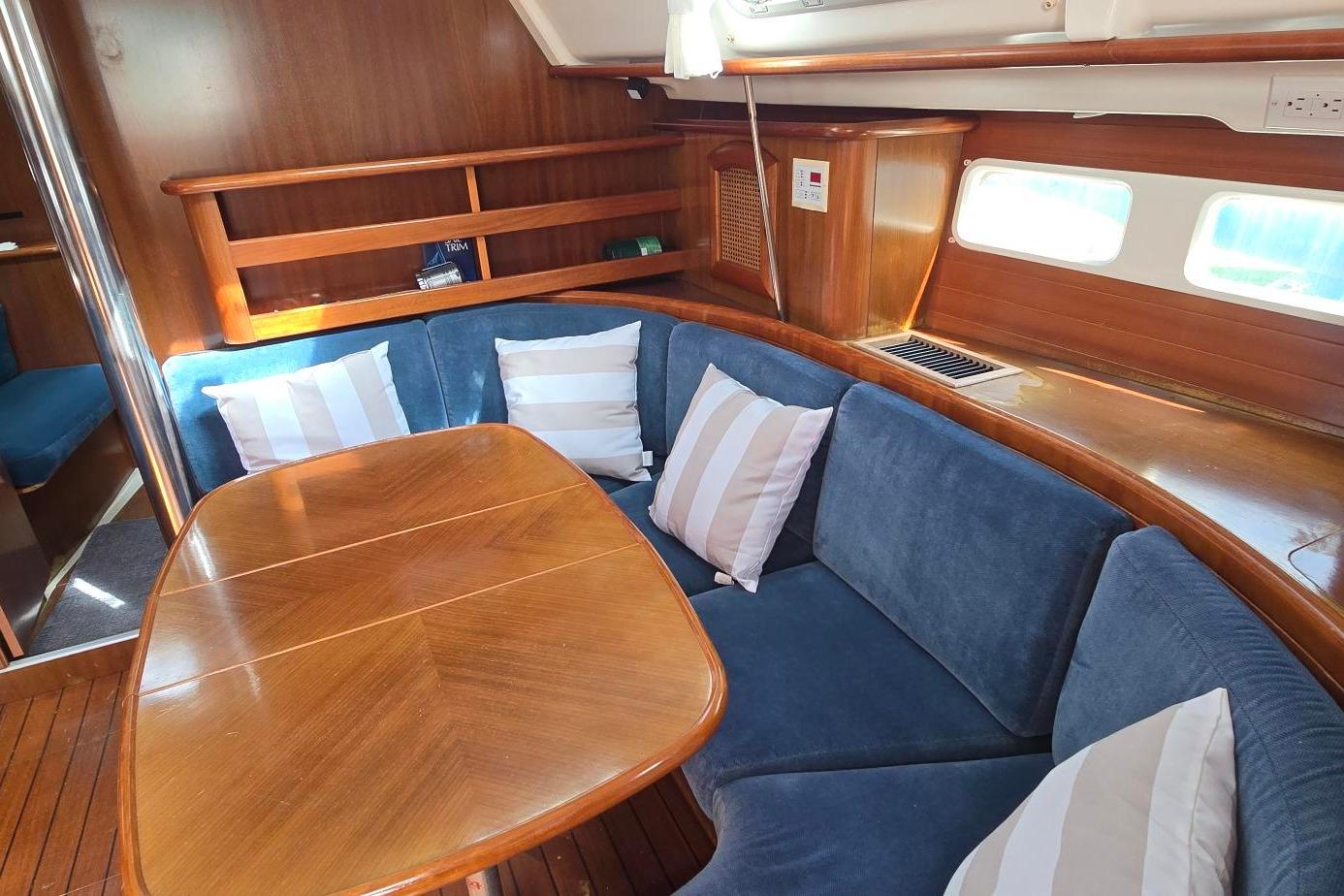 Interior of 1998 Beneteau Oceanis 411 yacht with blue seating and wooden table.