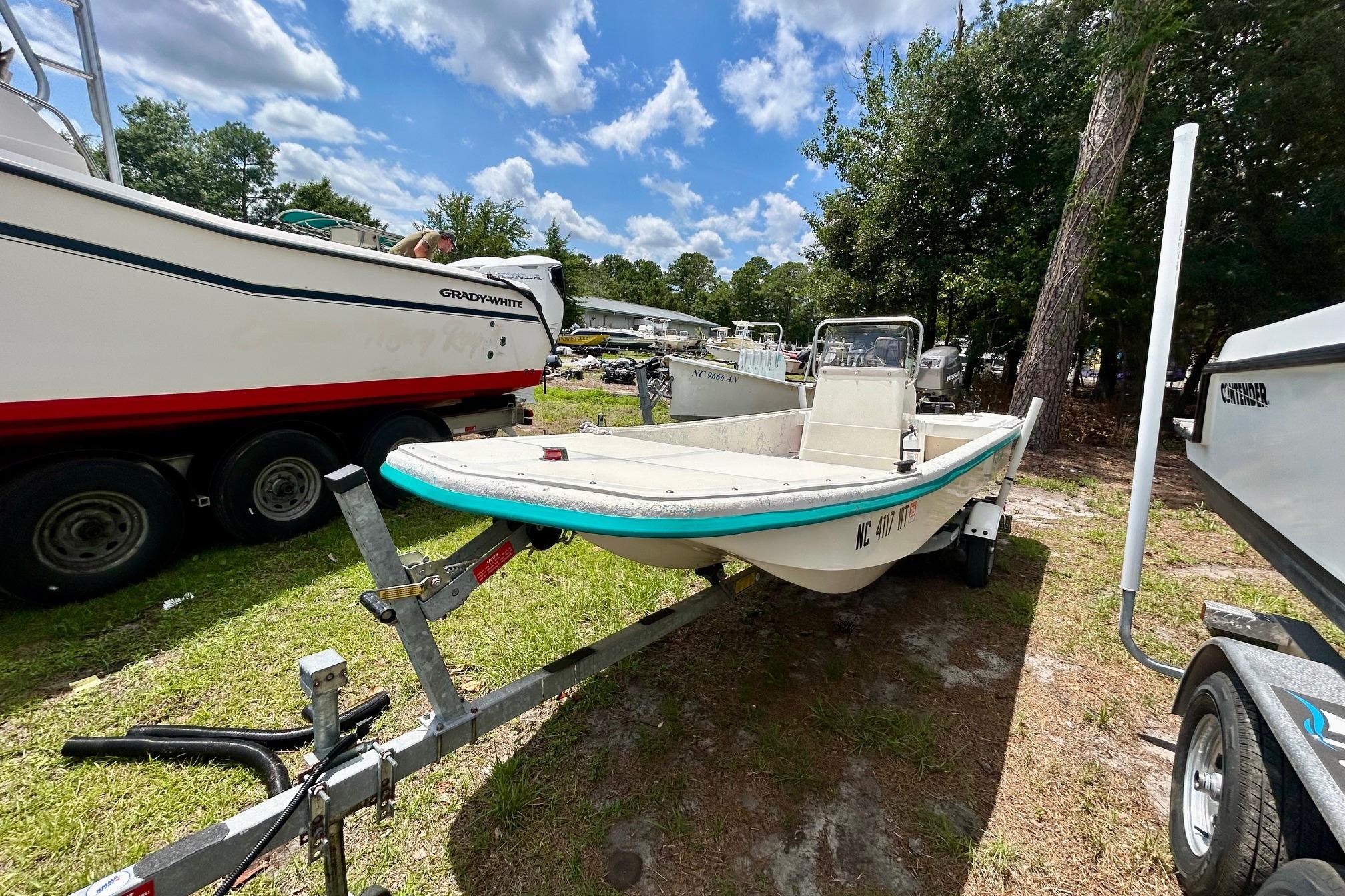 2002 Sundance K16CC boat on trailer, parked outdoors under a partly cloudy sky.