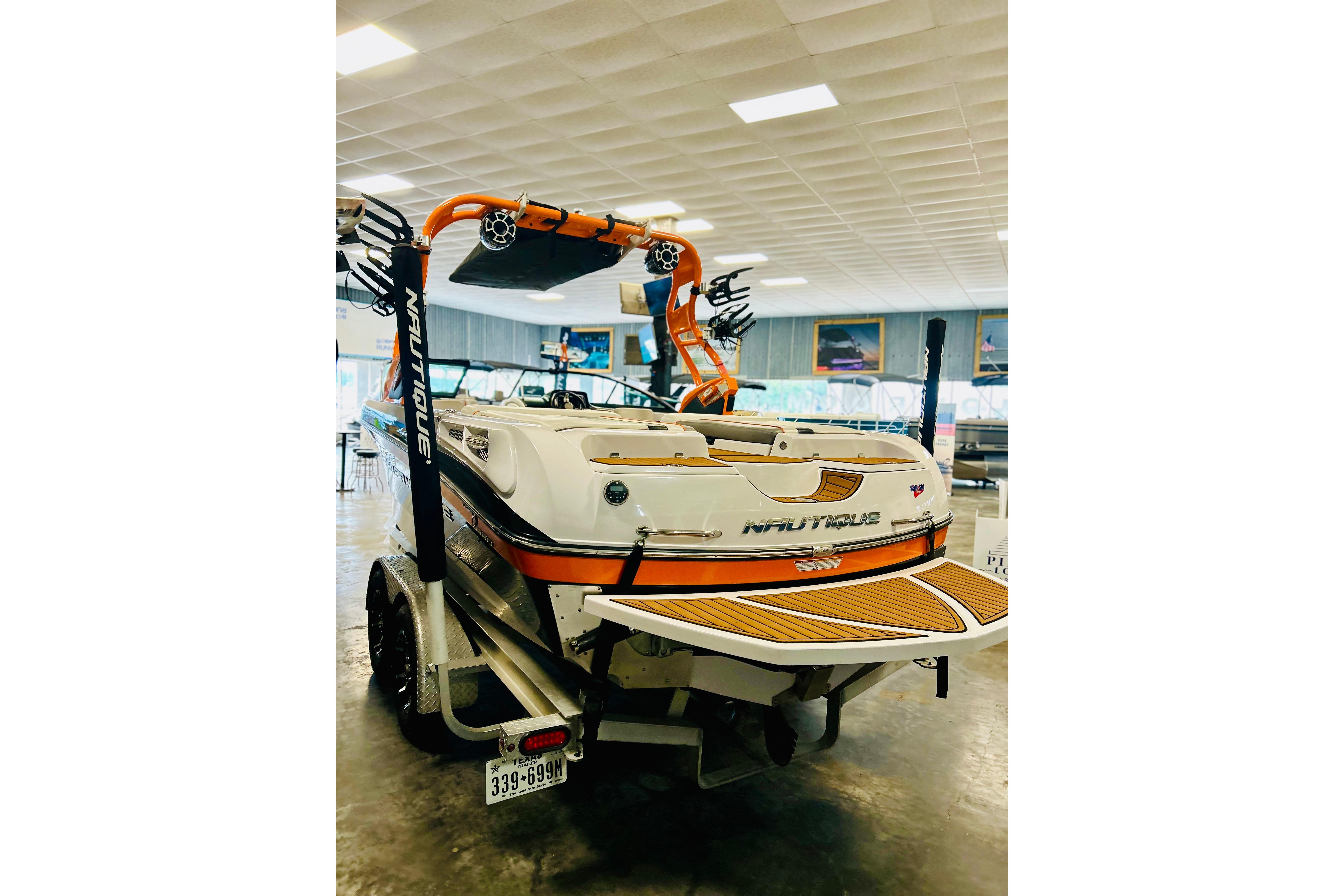 2013 Nautique Super Air Nautique 230 boat in showroom, featuring vibrant orange accents.