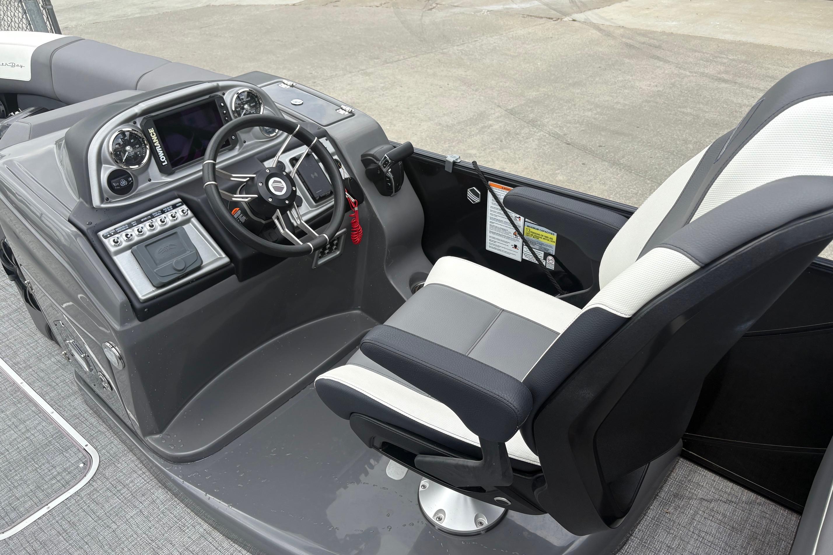 Captain's helm of 2023 South Bay 525 RS 3.0 Arch boat with steering wheel and controls.
