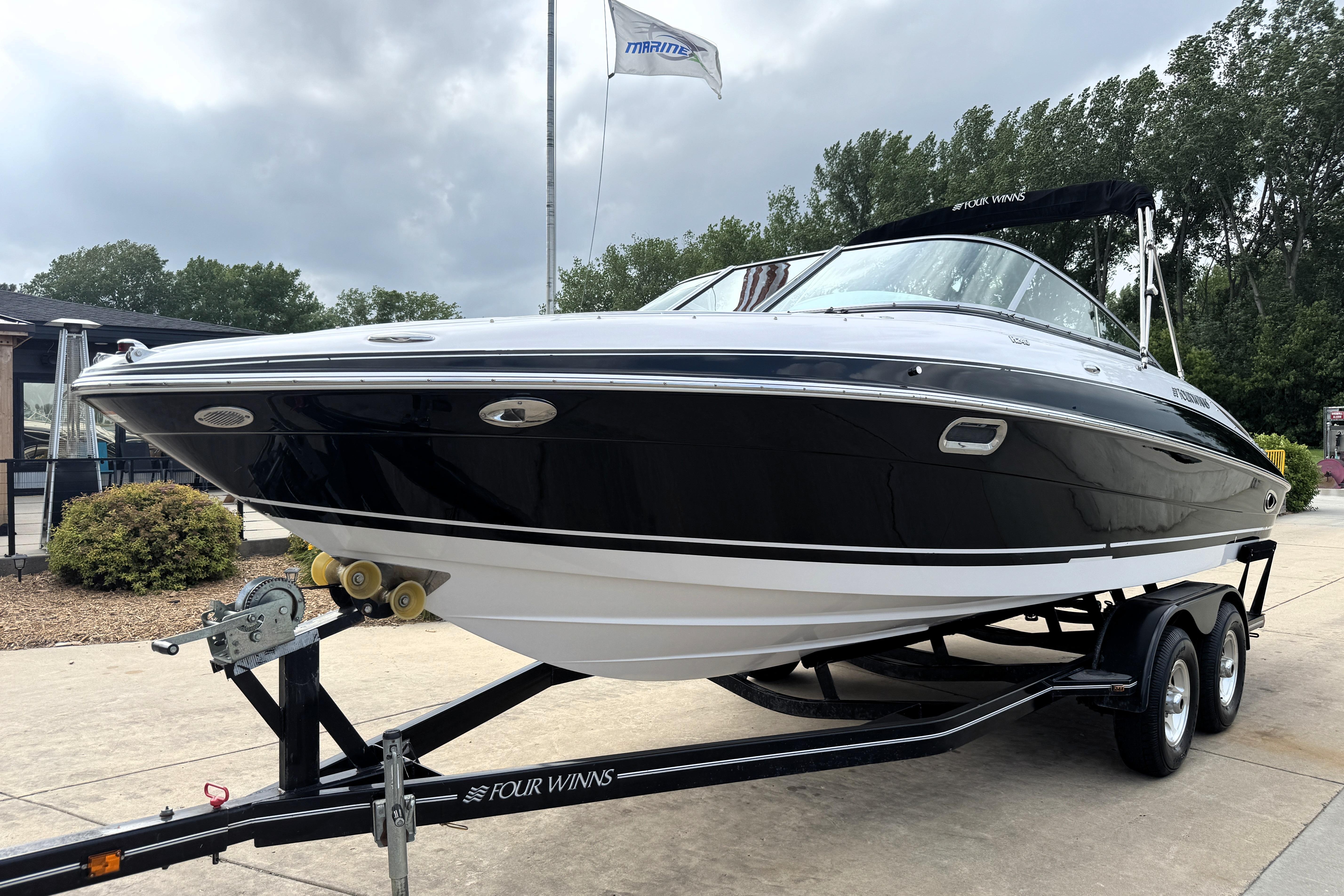 2008 Four Winns H240 boat on trailer, sleek black design, parked outdoors.