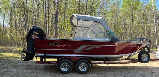 2016 Alumacraft Trophy 205 Sport boat parked in forest.