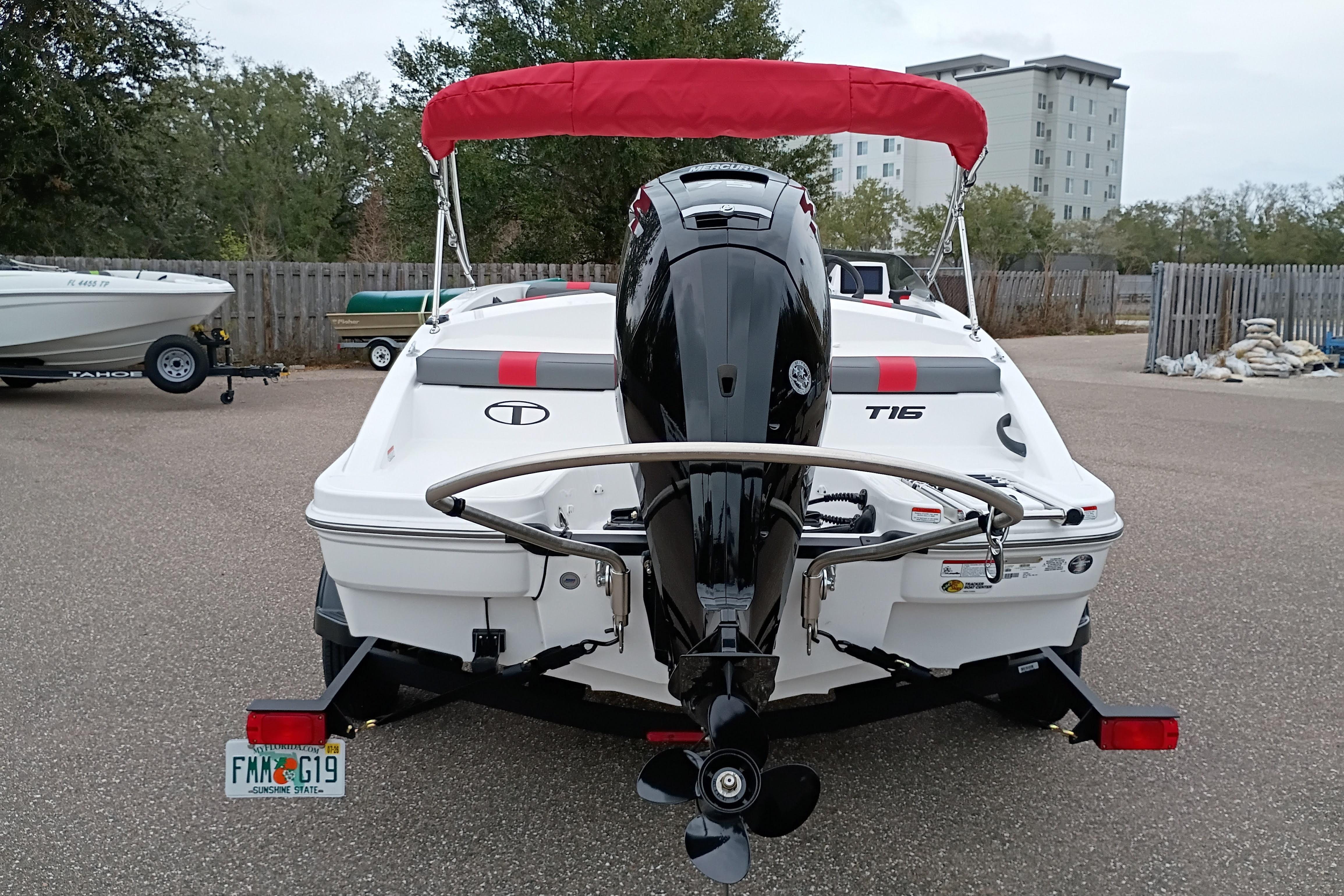 2026 Tahoe T16 boat with red canopy and outboard motor, parked in a lot.