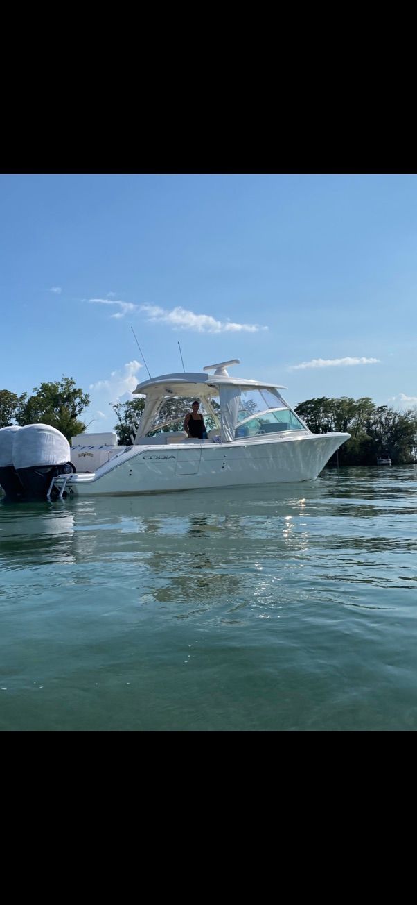 2023 Cobia 330 boat on calm water under sunny skies.