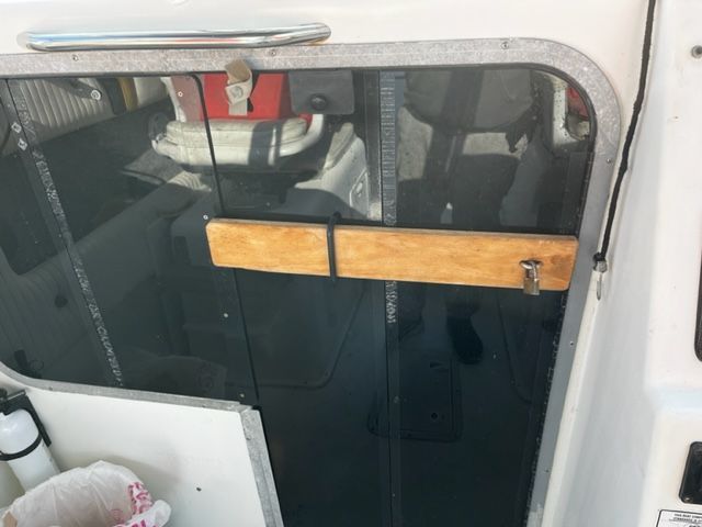 The door of a 1998 Sport-Craft 252 Sport Fish boat with a wooden latch.