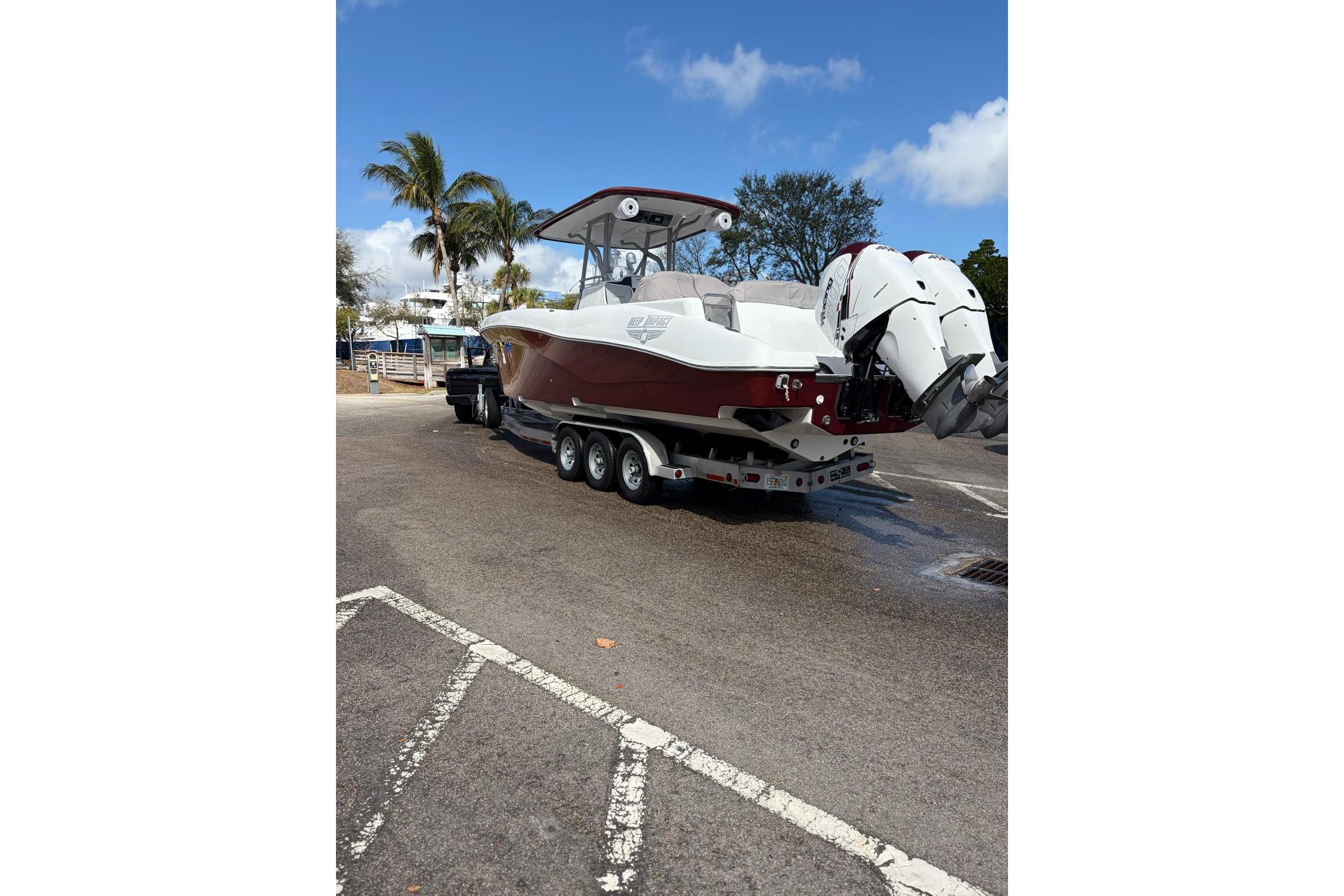 2015 Deep Impact 33 boat on trailer, parked near palm trees under blue sky.