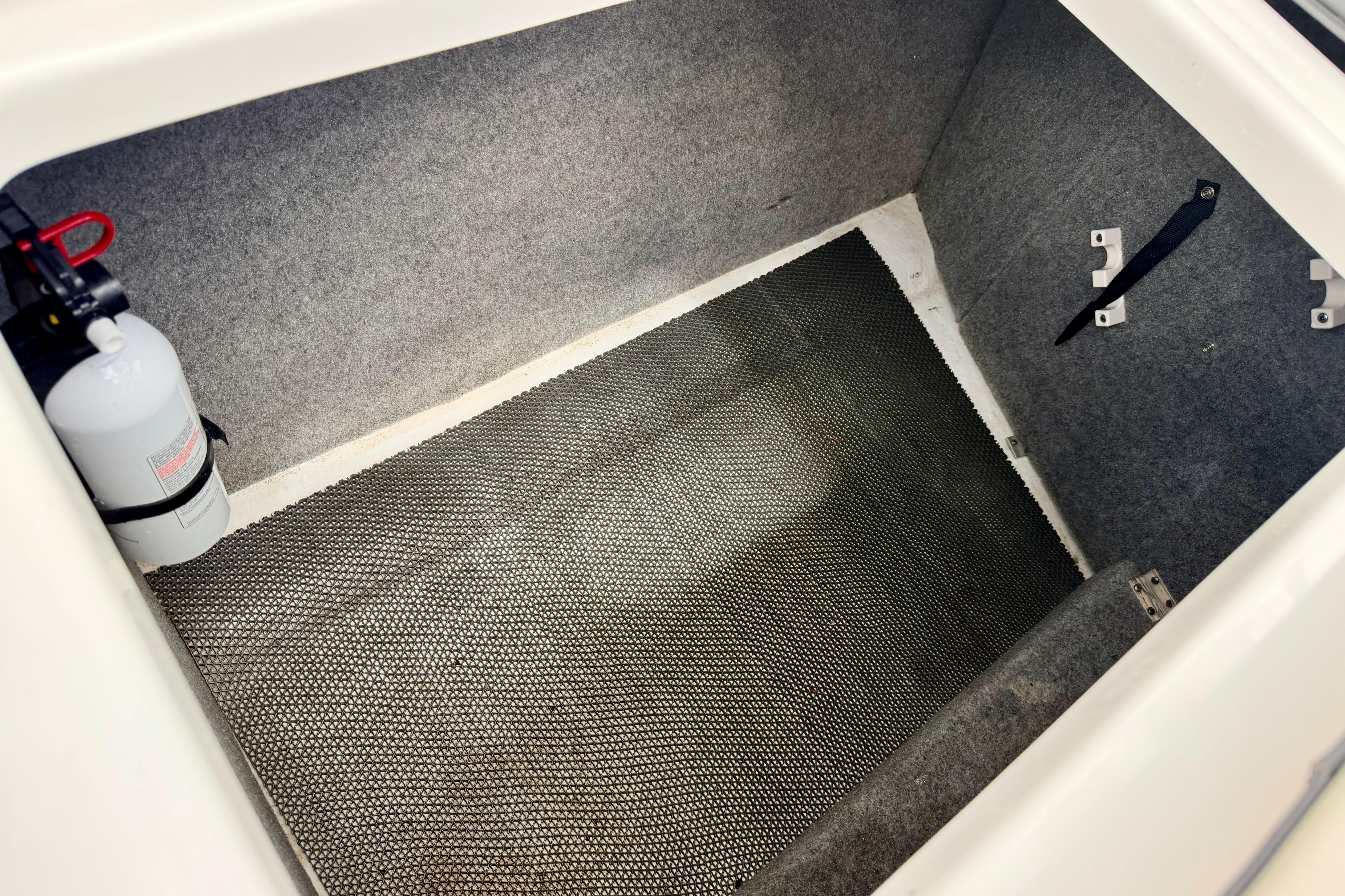 2015 Chaparral Sunesta 264 storage compartment with fire extinguisher and carpeted interior.
