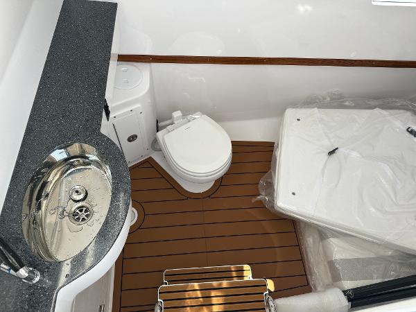 2025 Southport 33 FE boat interior with sink, toilet, and wooden flooring.