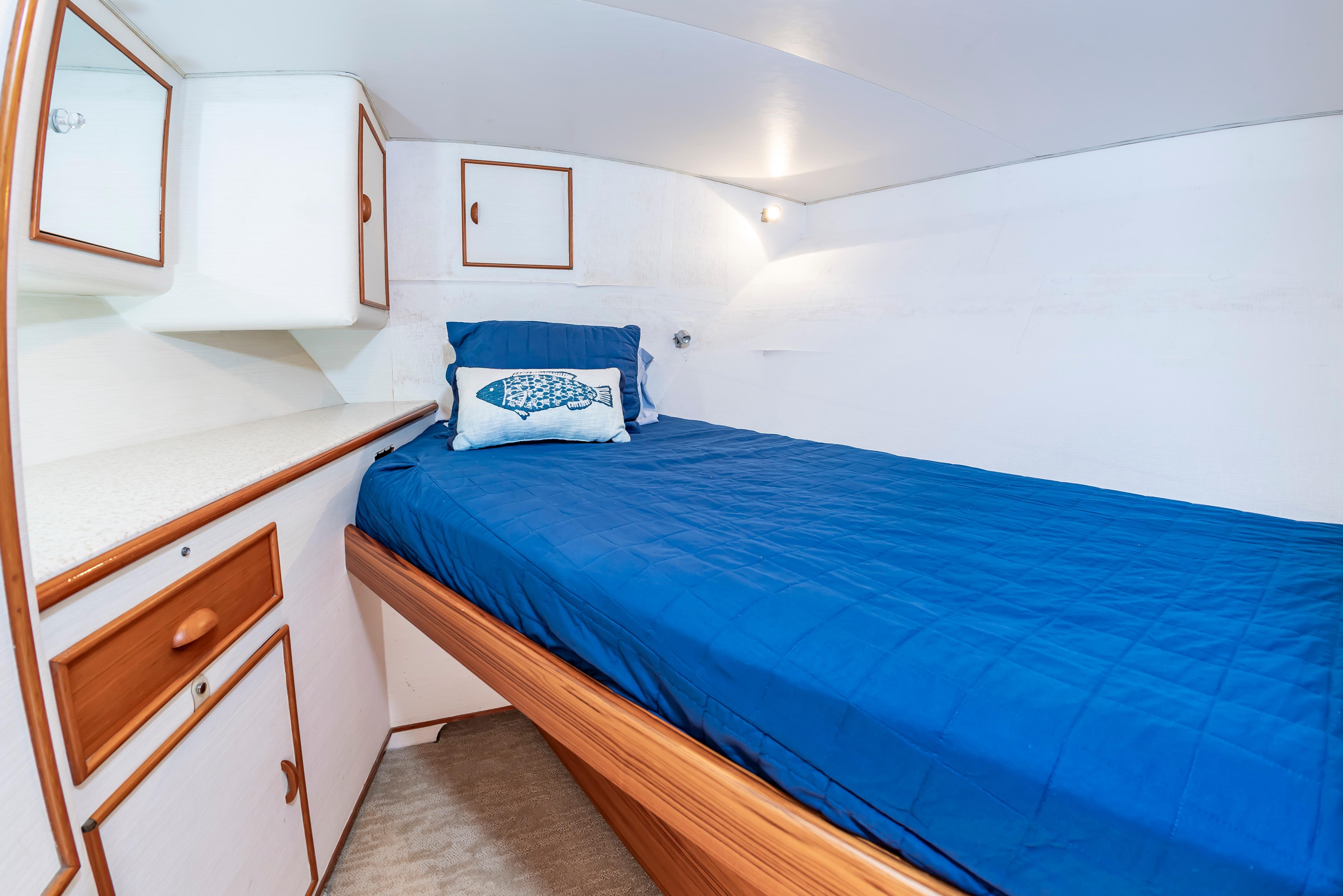Cozy cabin interior of 1993 Custom Carolina Scarborough 56 Convertible with blue bedding and wooden accents.