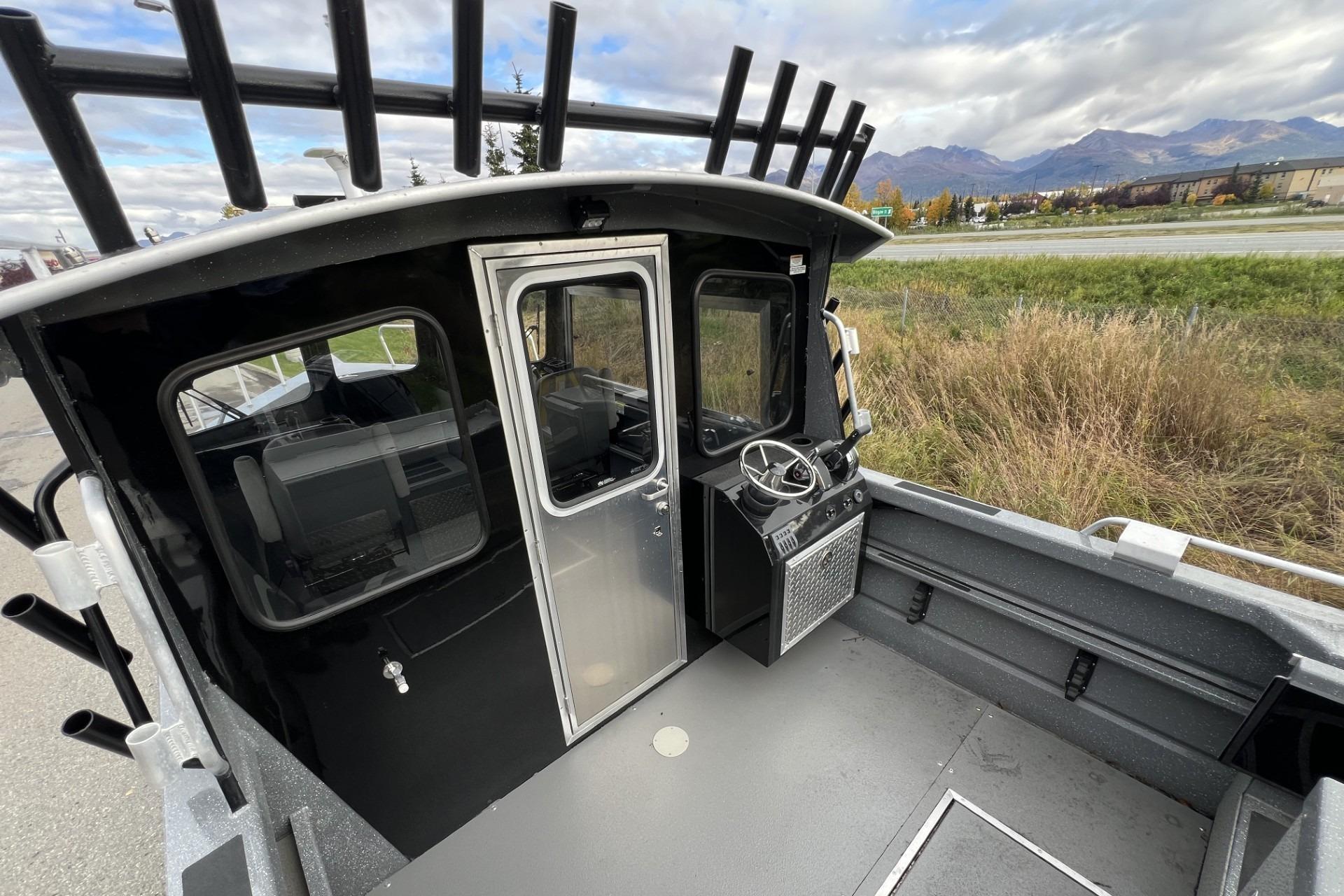 2024 Spartan 220 Maximus boat cockpit with steering wheel, outdoor setting, and mountainous background.