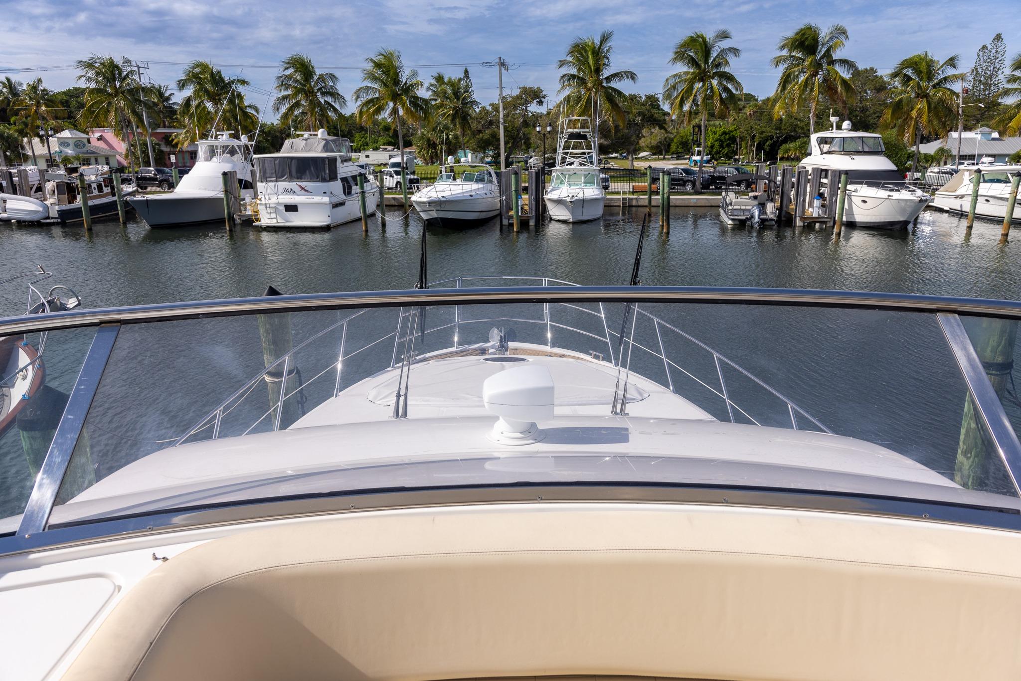 View from Azimut 54 Flybridge yacht, 2014 model, overlooking marina with palm trees and boats.
