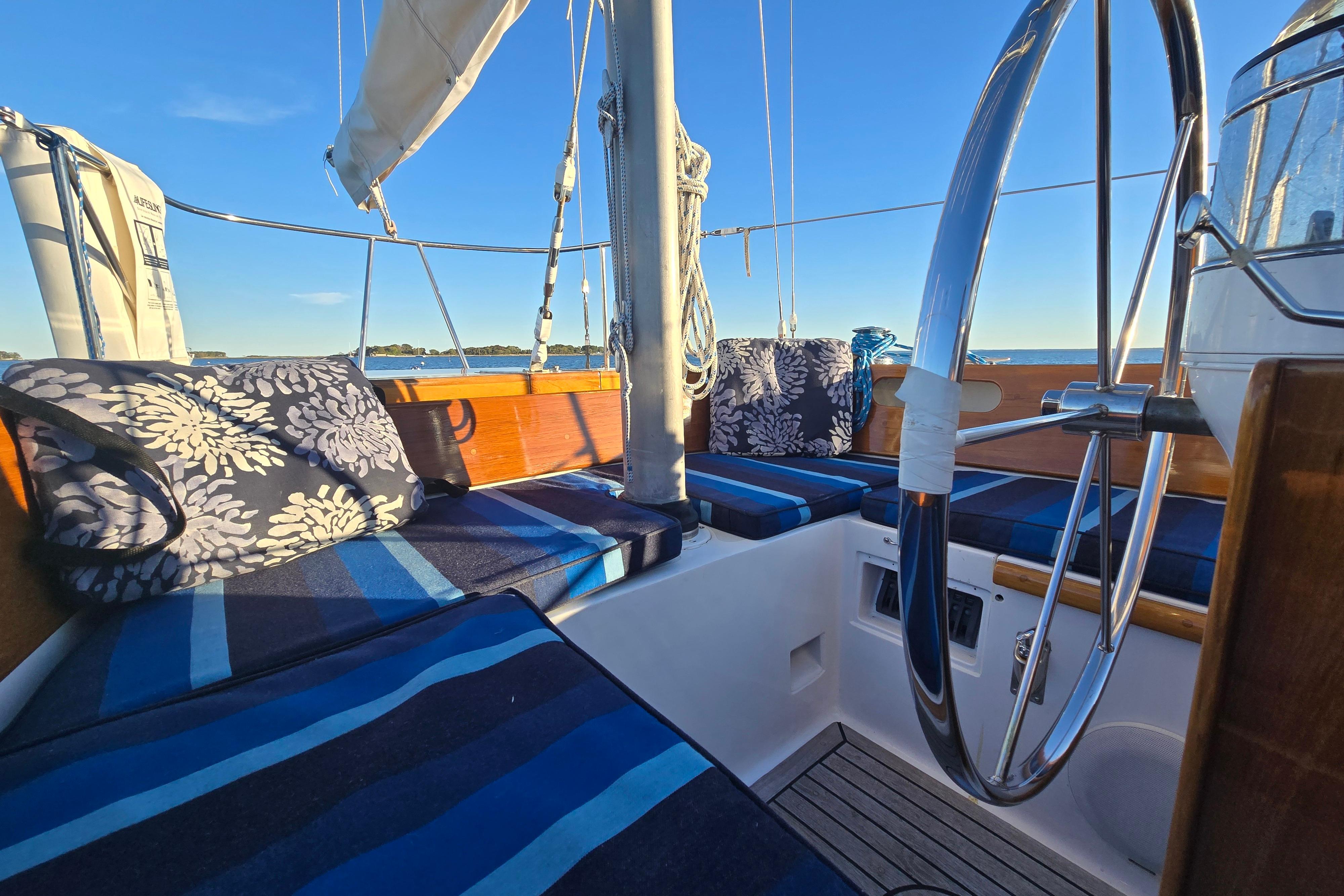 Cockpit of a 1970 Hinckley Bermuda 40 sailboat with striped cushions and a steering wheel.