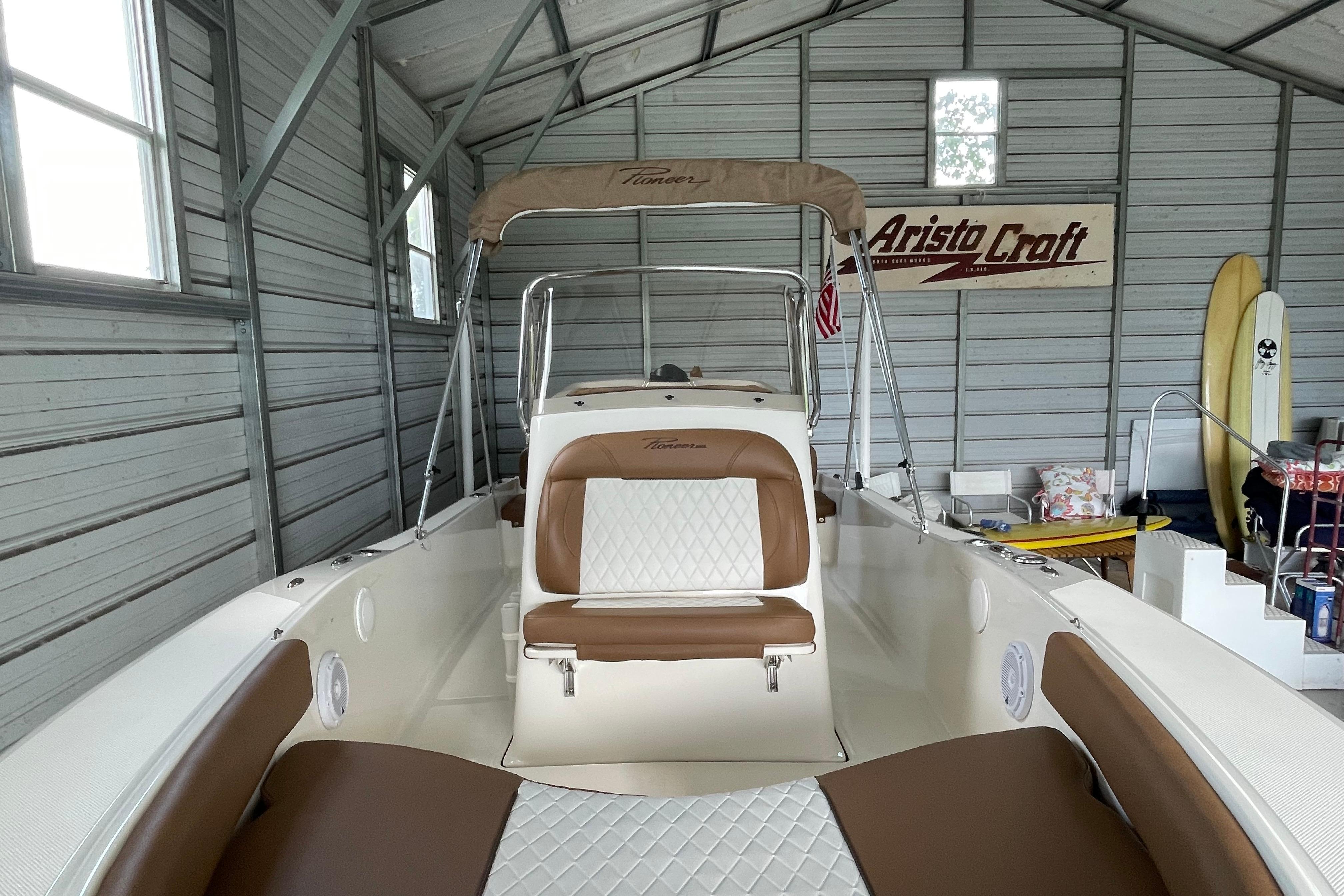 2024 Pioneer 180 Islander boat in a garage, featuring brown and white seating.