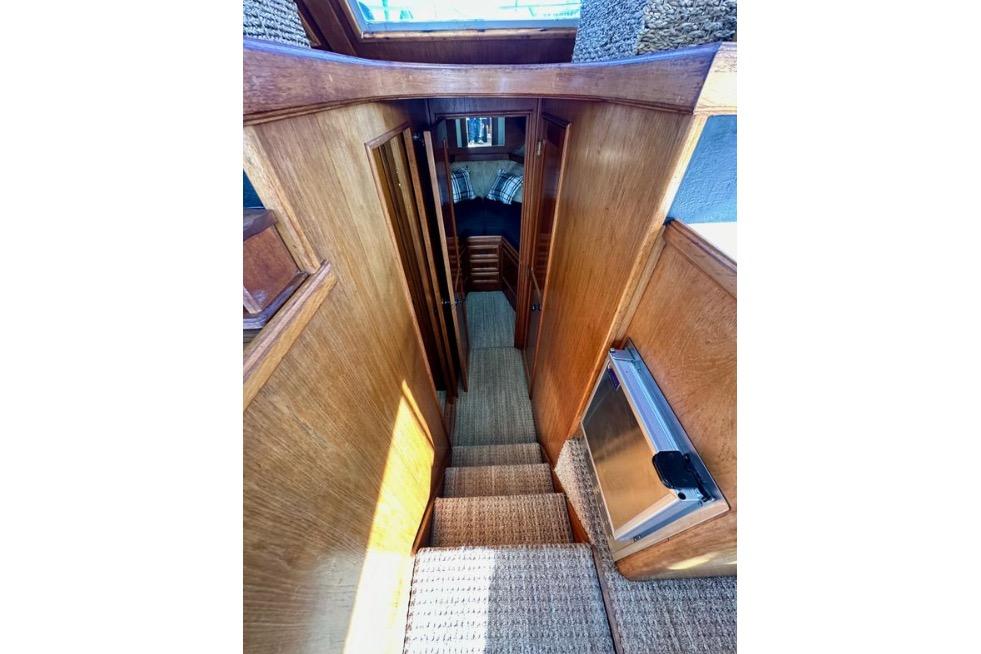 Interior view of 1985 Egg Harbor 33 Sedan, featuring wooden stairs and cozy cabin.