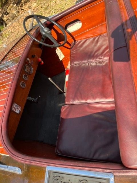 Interior of a 1938 Chris-Craft Custom Deluxe Runabout with red leather and wood paneling.
