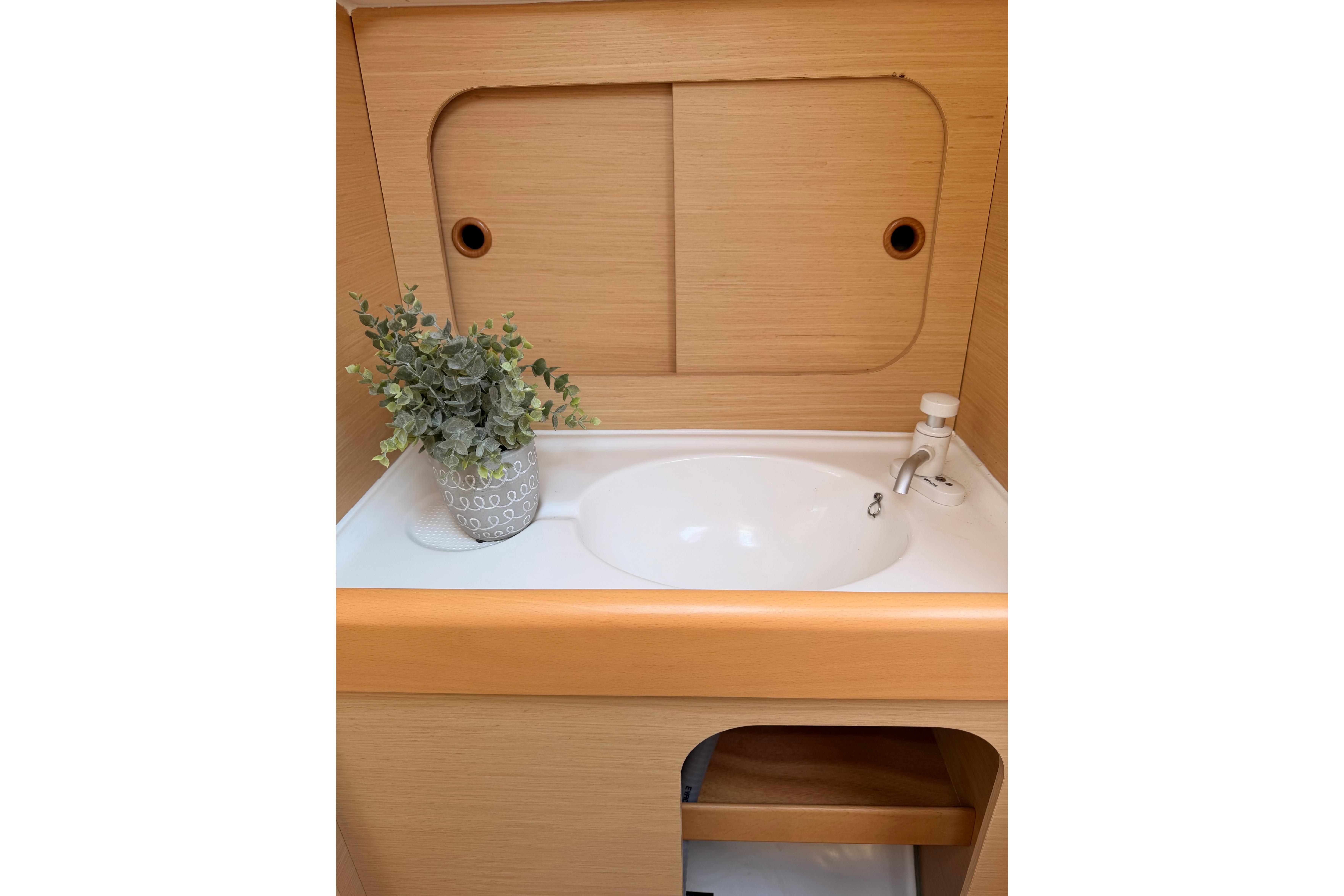 Beneteau FIRST 25 S 2014 yacht interior with sink and decorative plant.
