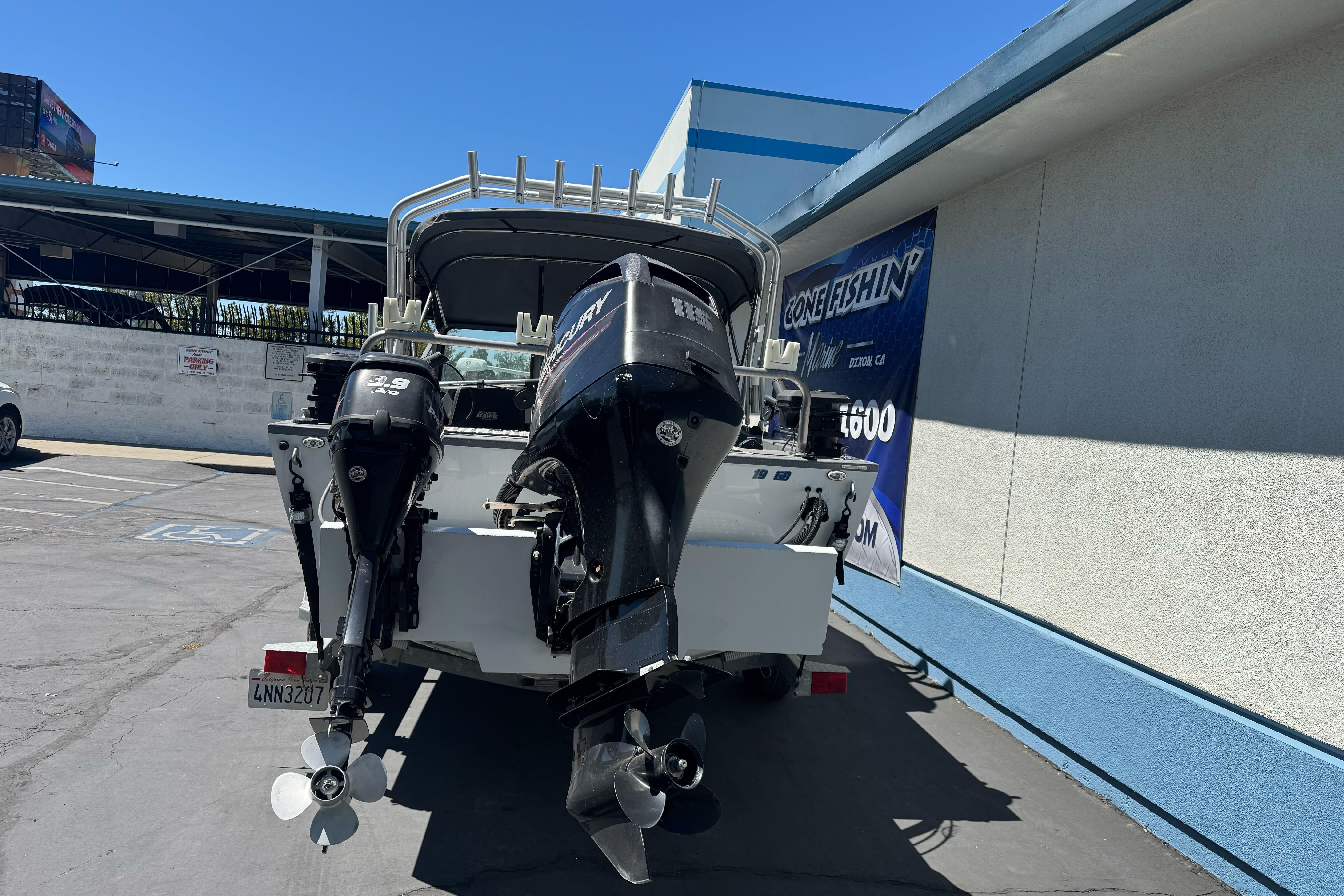 2014 River Hawk 19 GB boat with dual Mercury outboard motors in a parking lot.