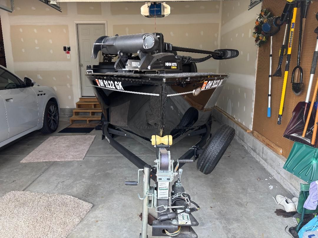 A black Lund Advent boat, model year 2022, is parked in a garage.