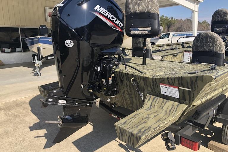 2026 Lund 1870 Predator SC boat with Mercury outboard motor, camo design, parked outdoors.