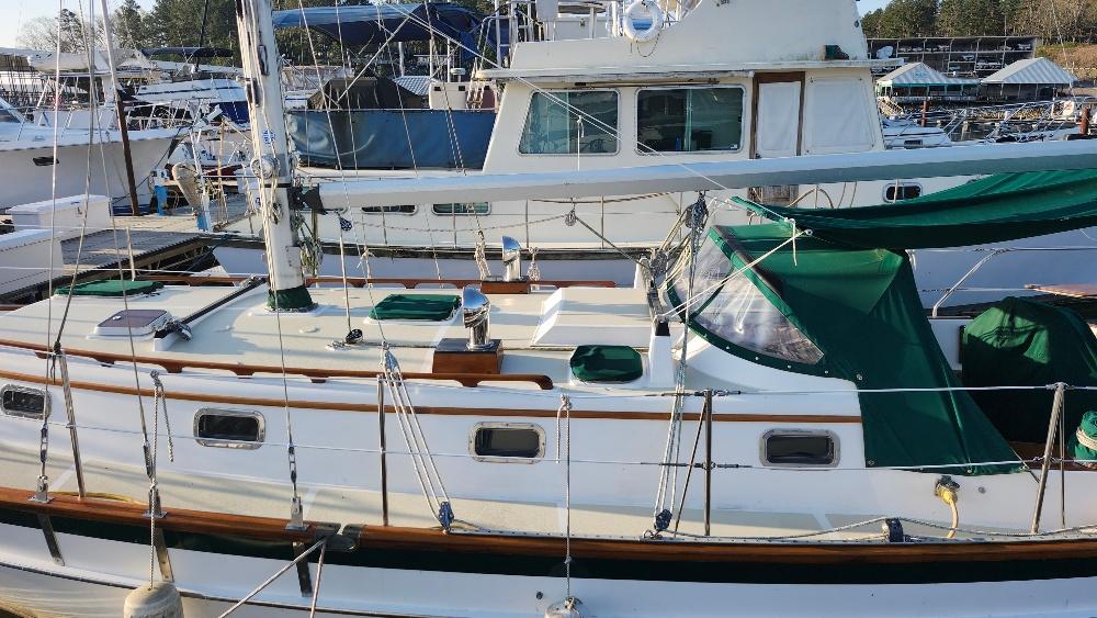 1989 Cabo Rico 34 sailboat docked, featuring green canvas covers and classic wooden accents.