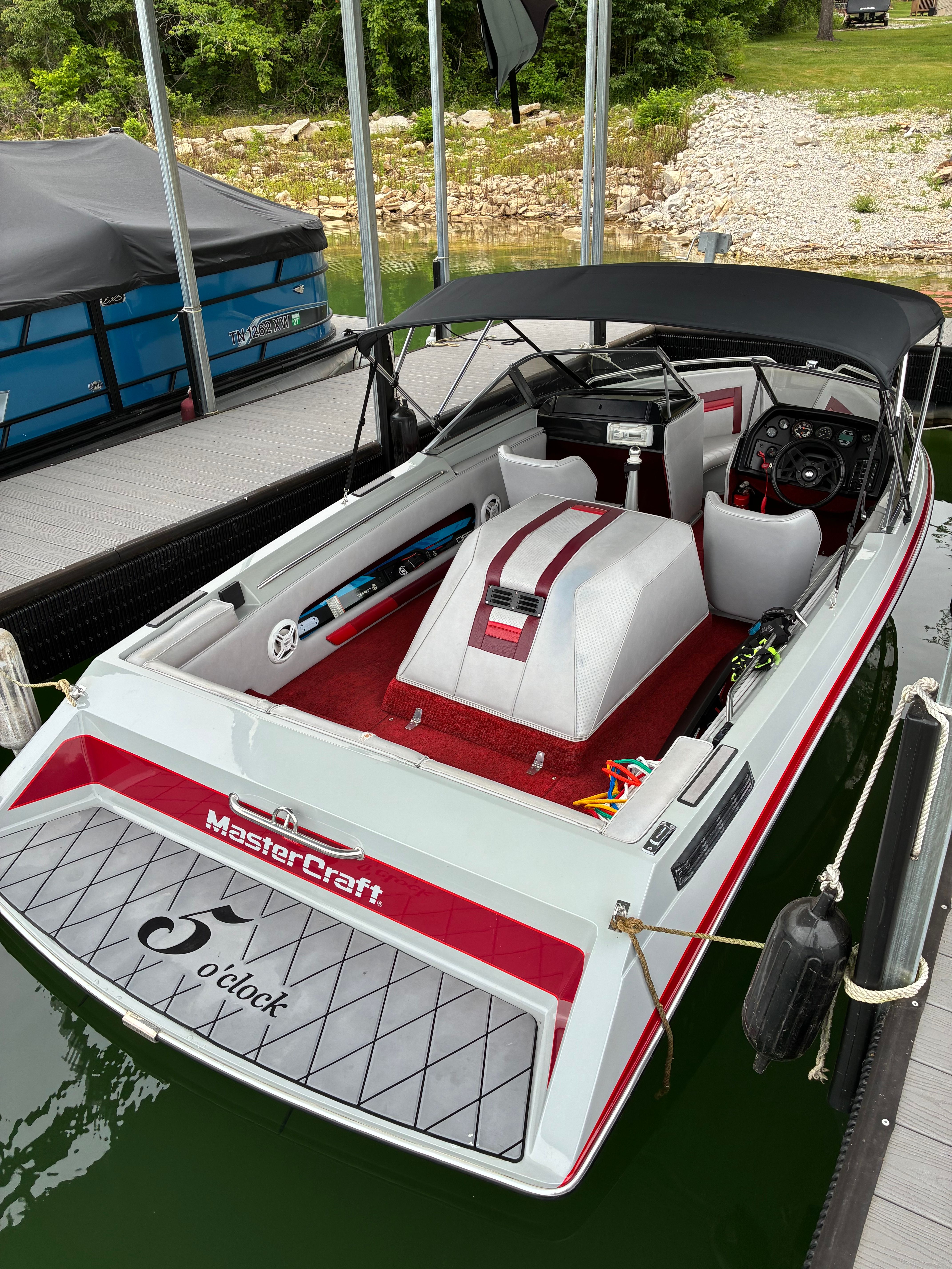 A 1989 MasterCraft TriStar 190 docked. It features a red interior and a black canopy.