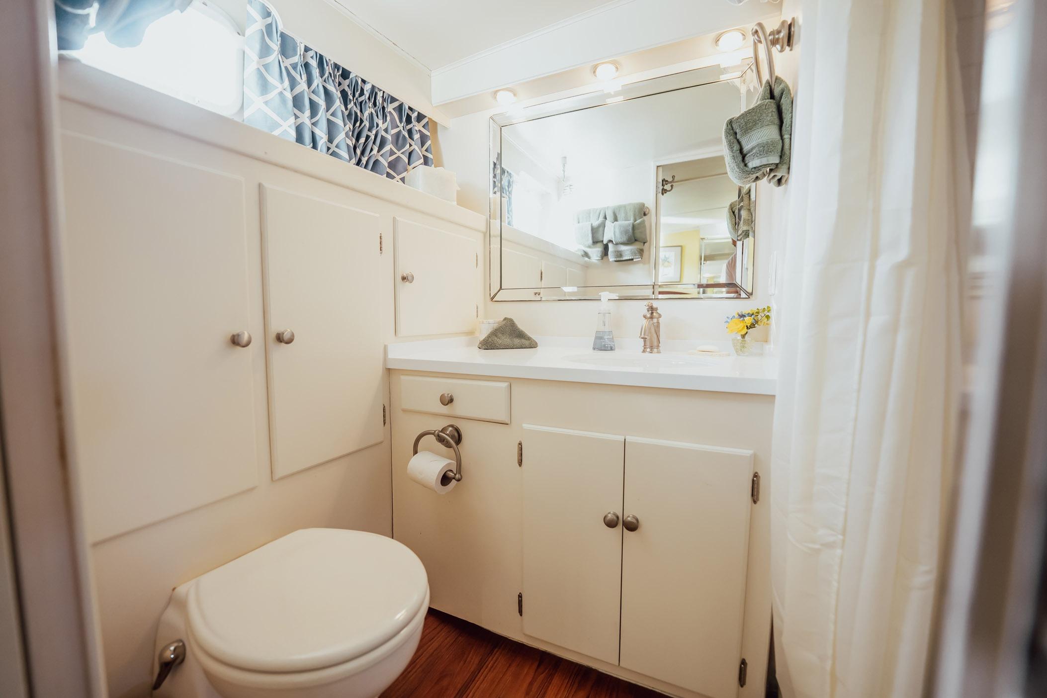 Bathroom interior of 1972 Trumpy 72 Motor Yacht with white cabinetry and mirror.