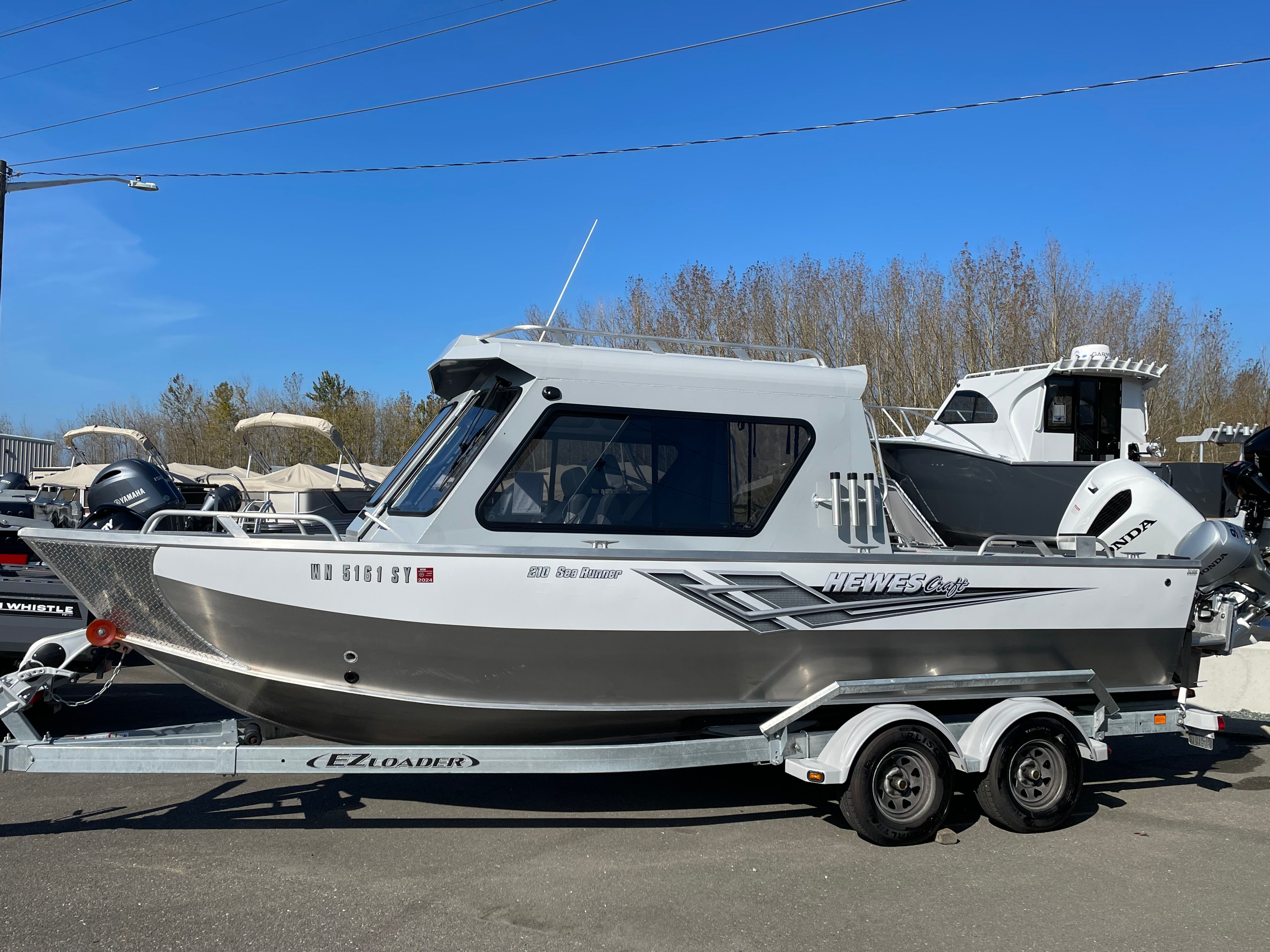 A silver 2021 Hewescraft 210 Sea Runner ET Hardtop sits on a trailer outdoors.