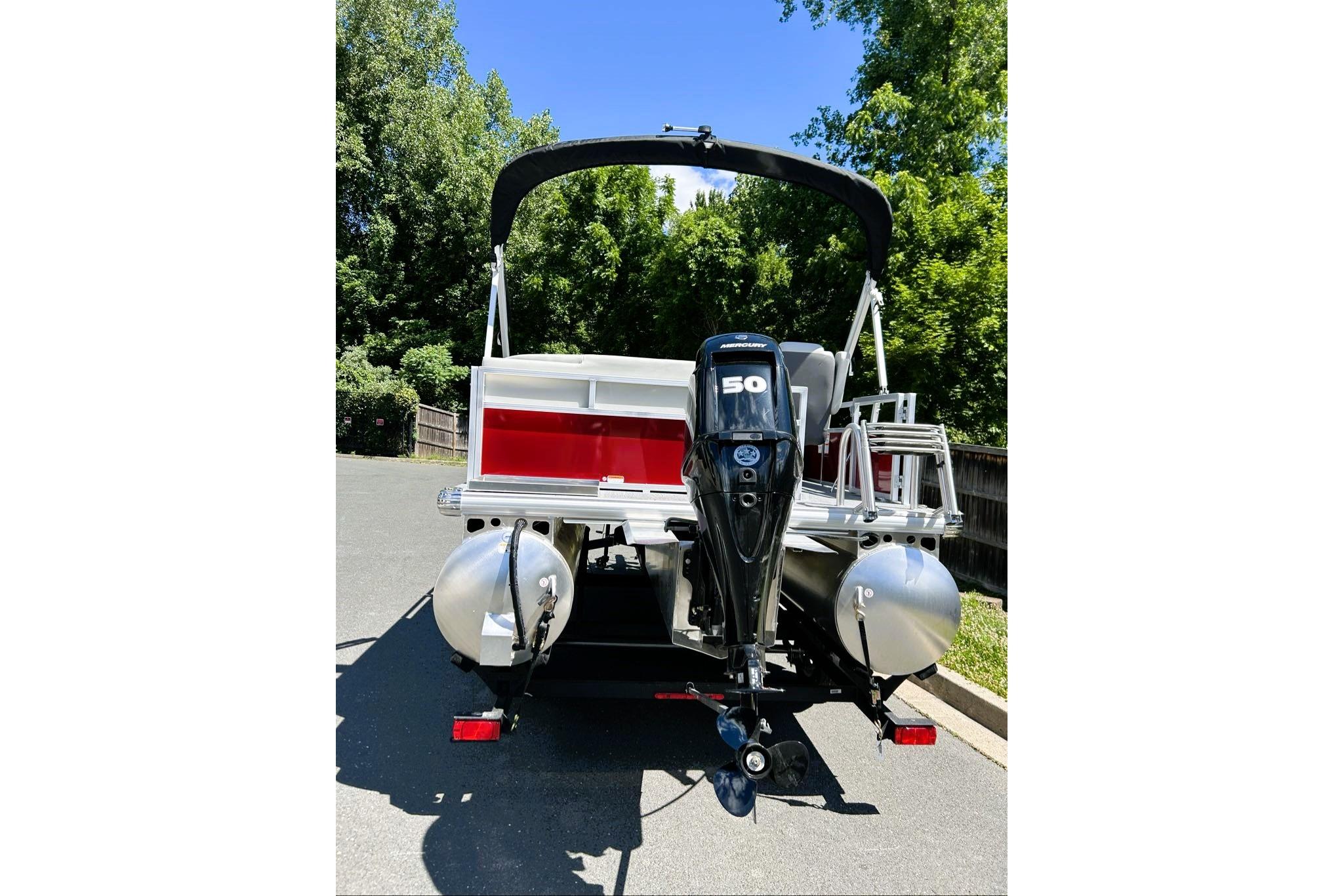 2026 Sun Tracker Bass Buggy 16 XL Select pontoon boat with 50 HP motor, parked outdoors.