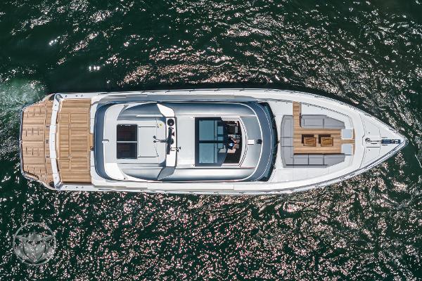 Aerial view of 2025 Riviera 645 SUV luxury yacht cruising on water.